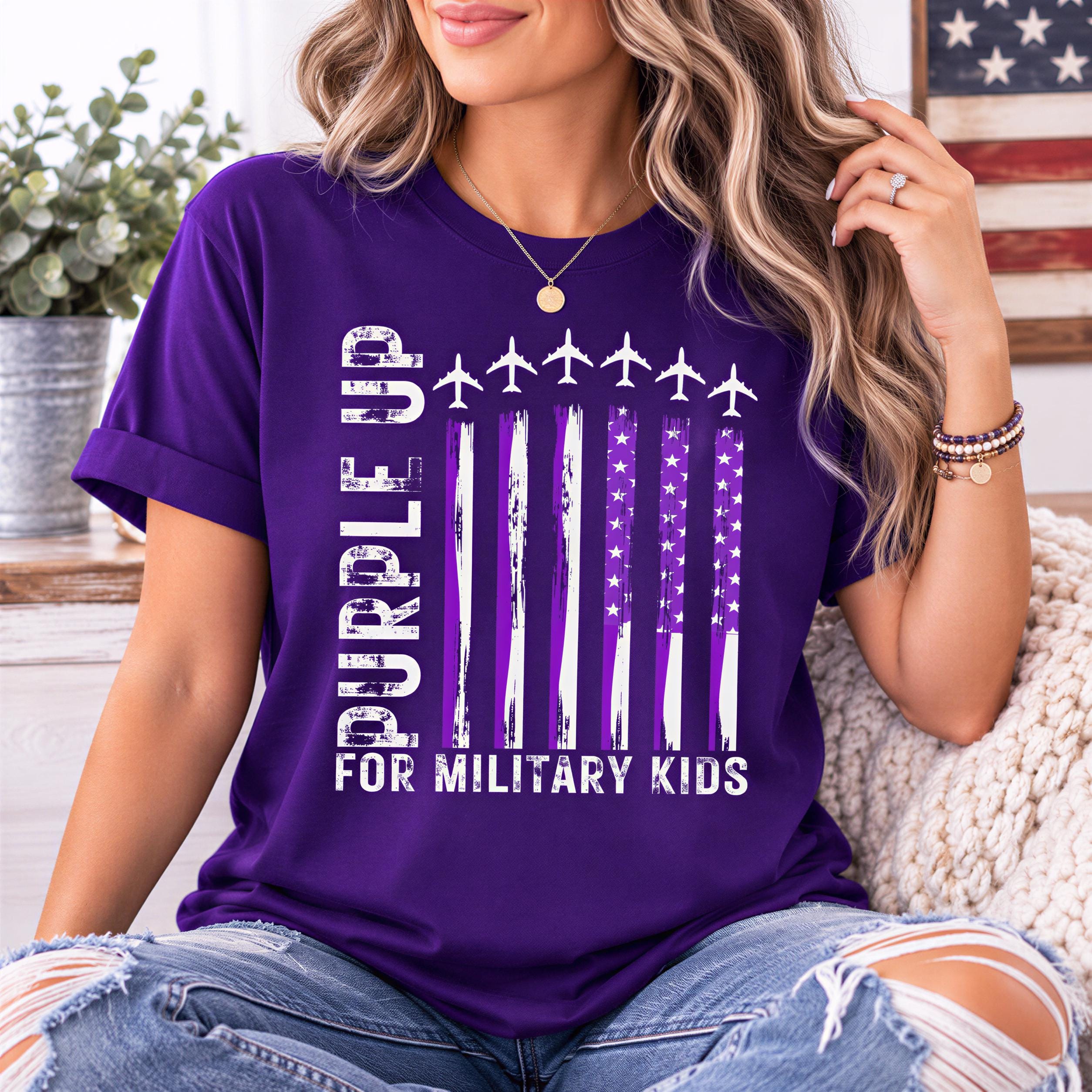 A woman wearing a purple t-shirt with a graphic design of a flag and text that says "Purple up for military kids".