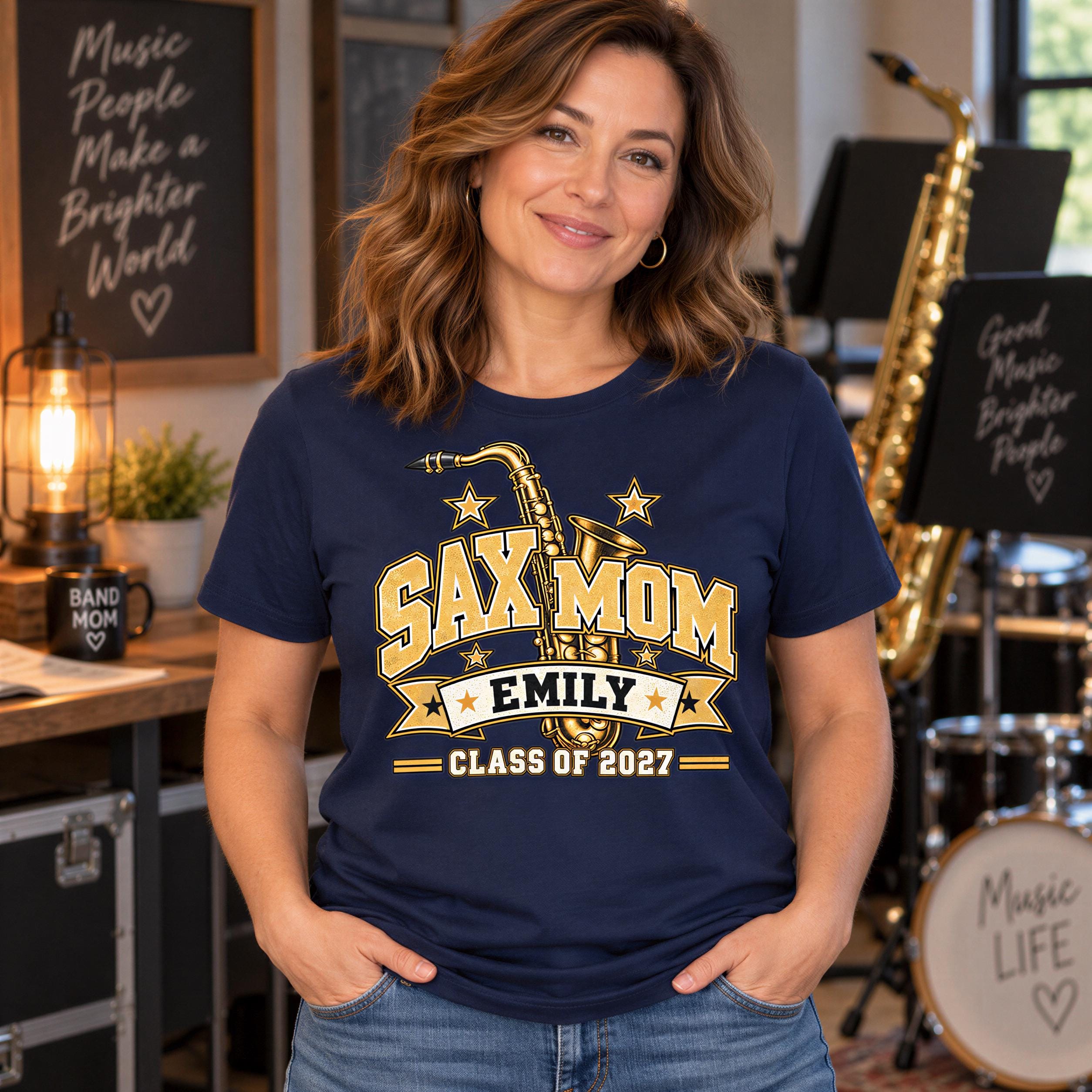 A woman wearing a navy blue t-shirt with a graphic design and text, standing in a room with musical instruments and a chalkboard.