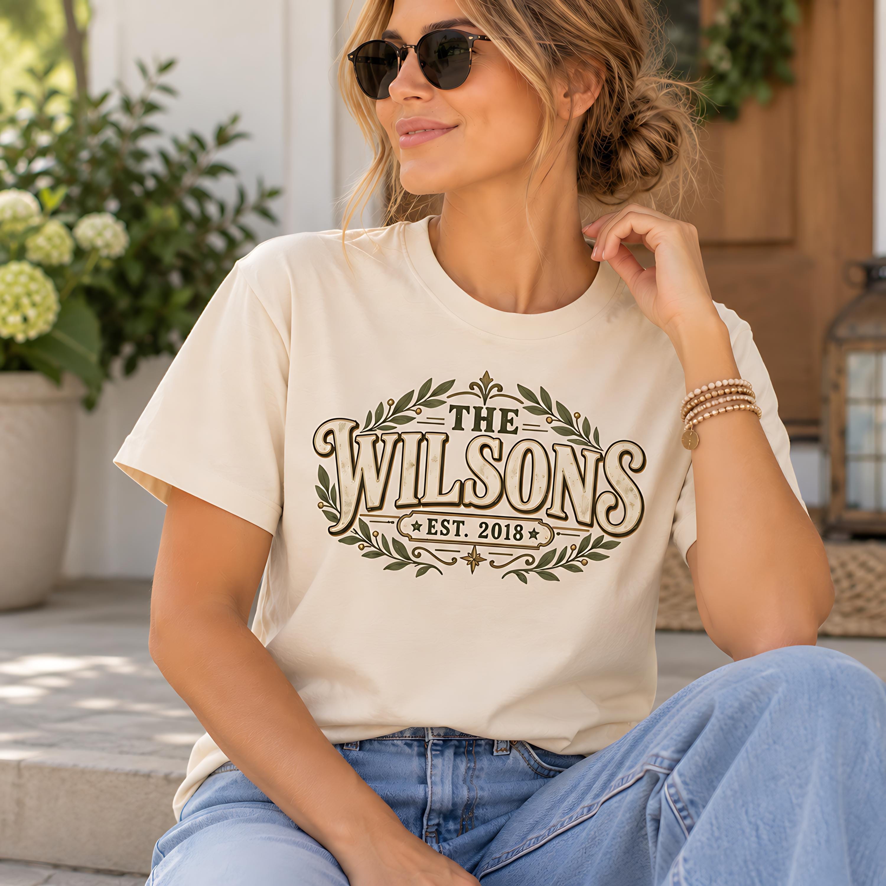 A woman wearing a white t-shirt with a graphic design and sunglasses is sitting on a step.