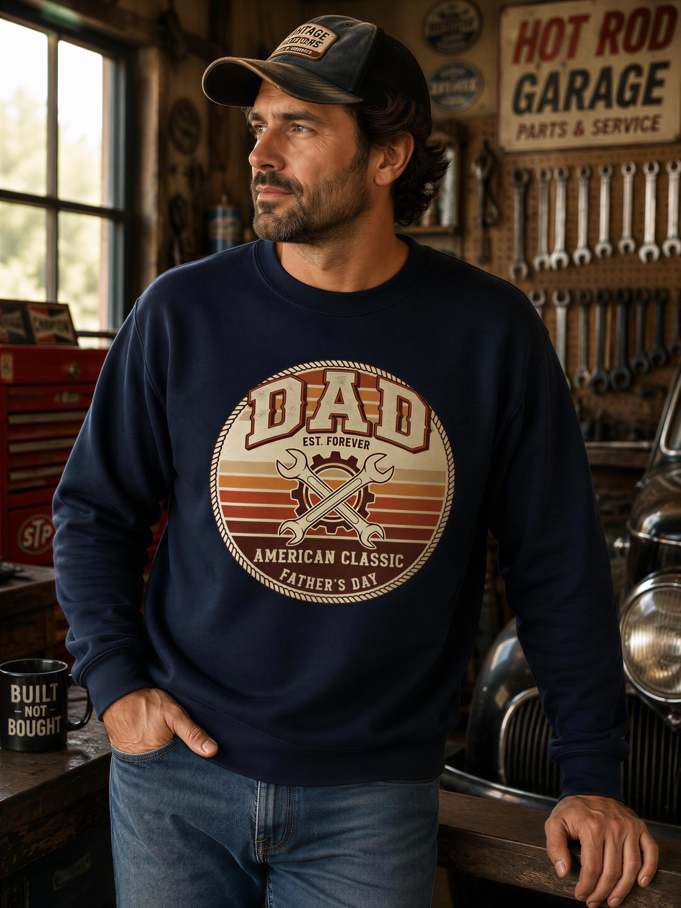 A man wearing a blue sweatshirt with a graphic design stands in a garage surrounded by tools and equipment.
