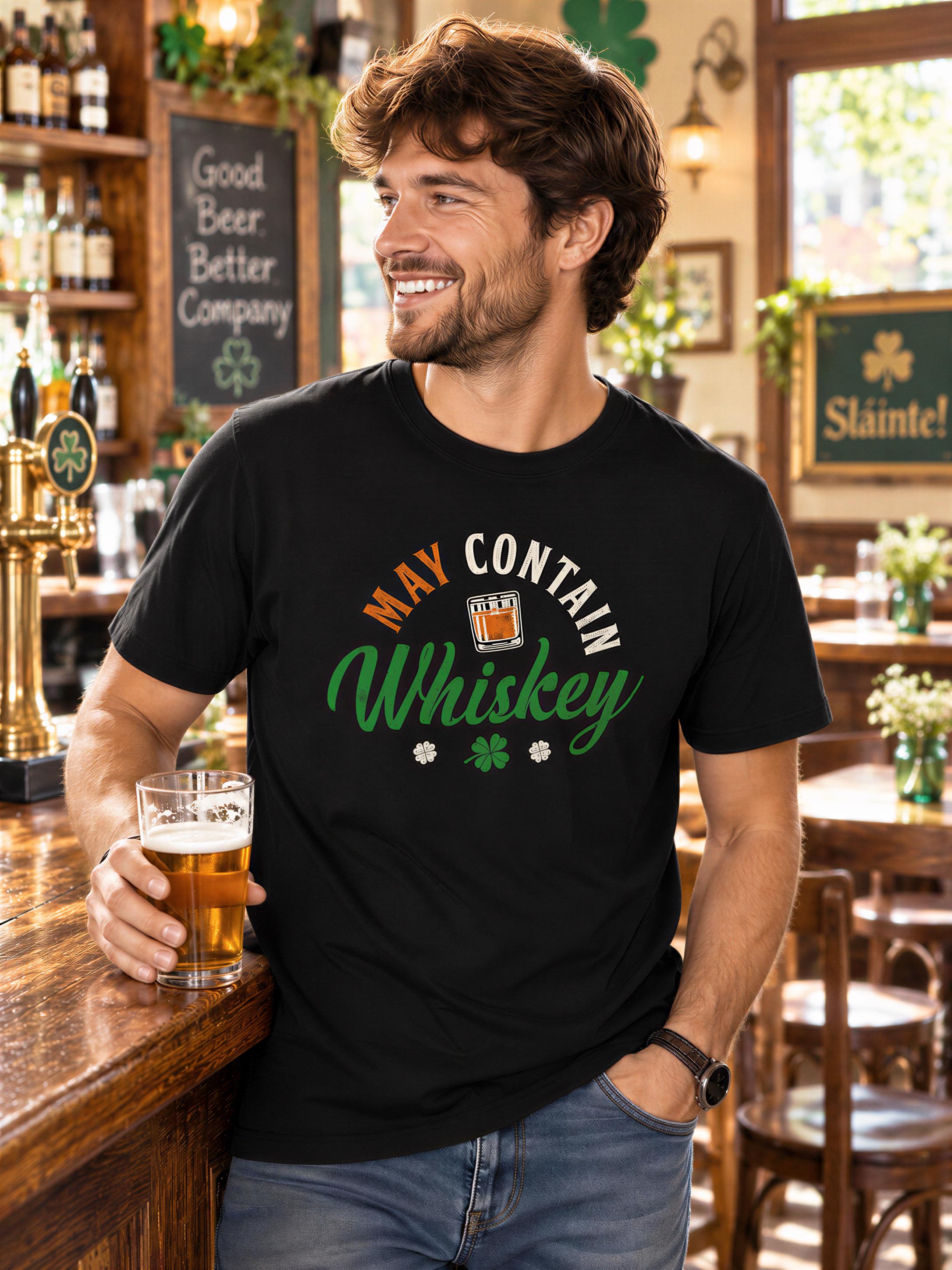 A man wearing a black t-shirt with the text "MAY CONTAIN WHISKEY" is standing in a bar, holding a glass of beer.