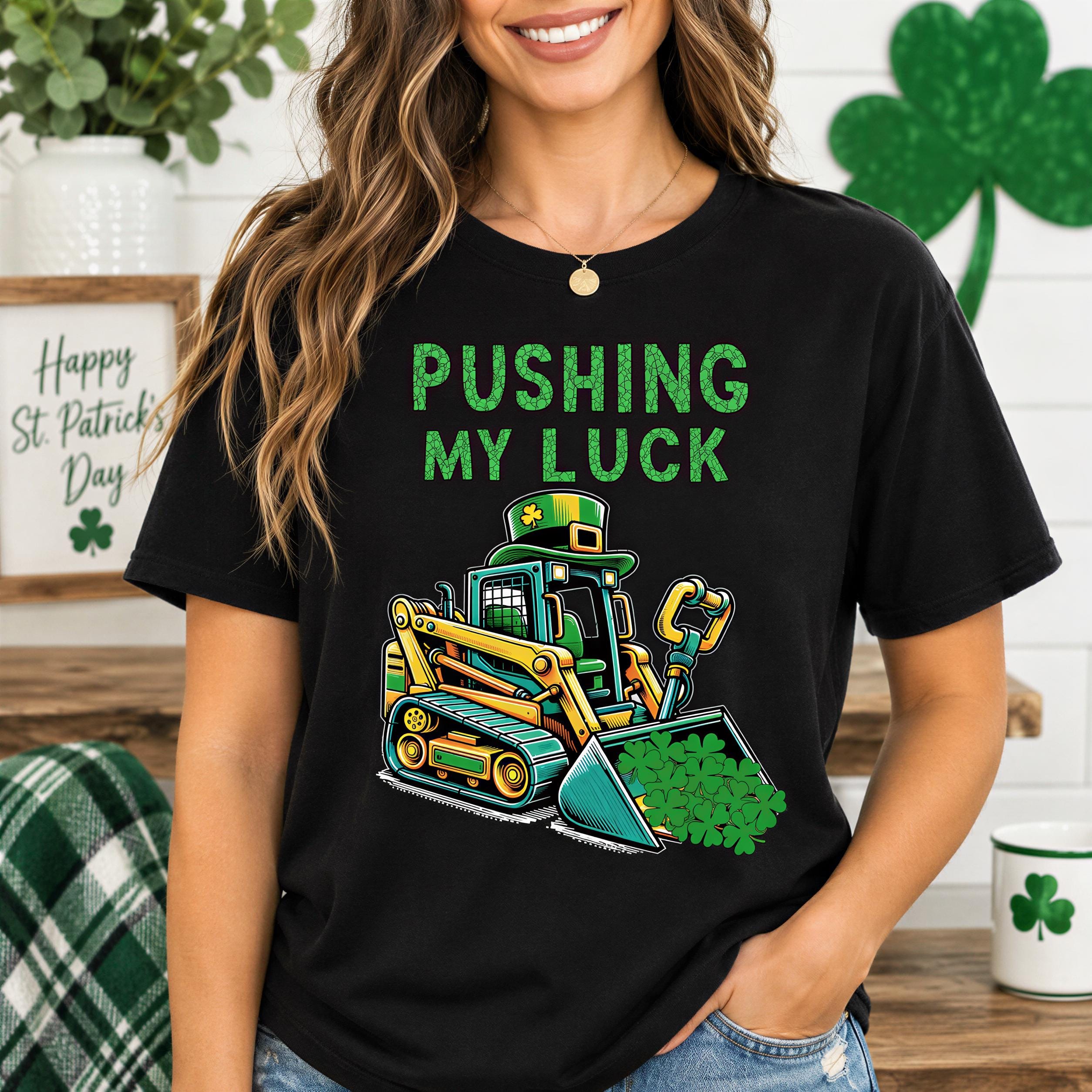 A woman wearing a black t-shirt with a graphic of a bulldozer and the text "PUSHING MY LUCK" printed on it.
