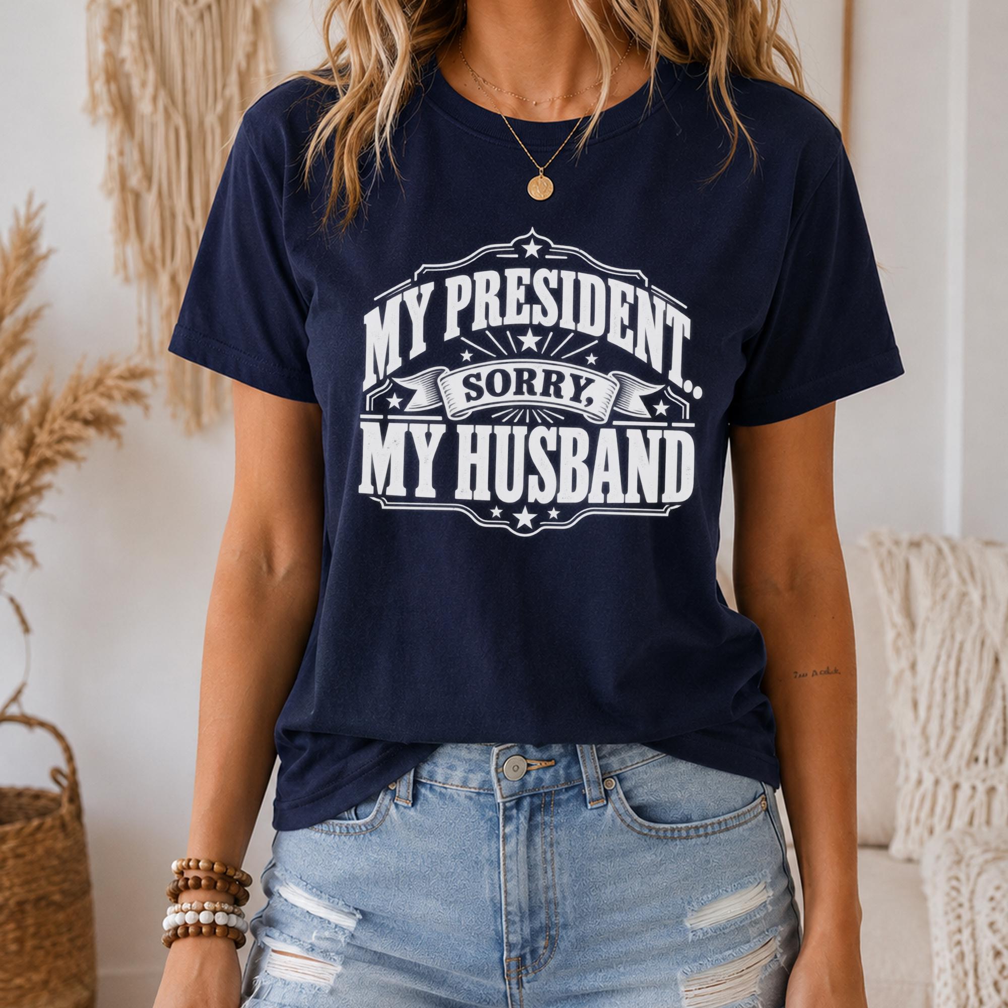 A woman wearing a navy blue t-shirt with a humorous text printed on it, standing in front of a beige wall with a woven basket.