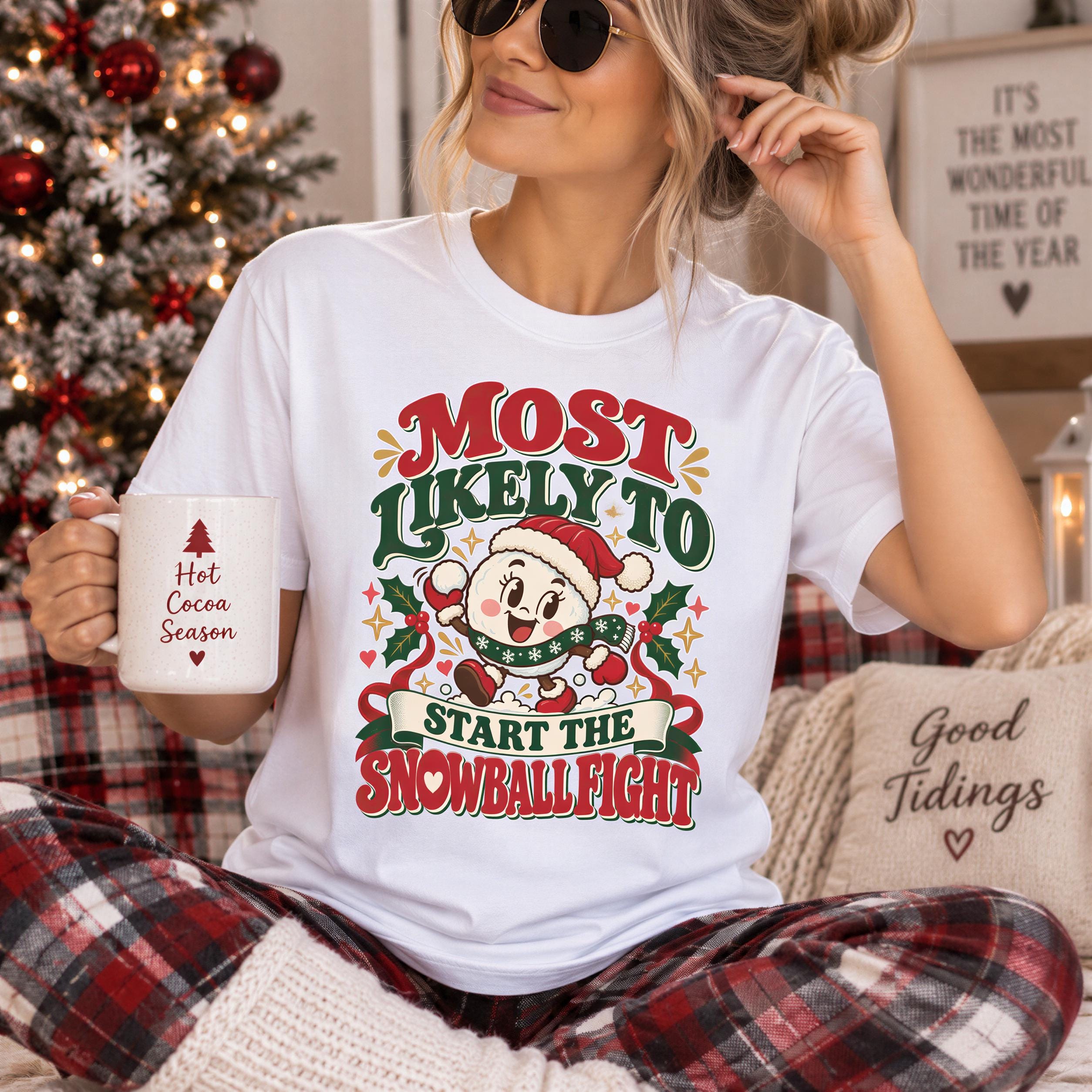 A woman wearing a white t-shirt with a humorous Christmas-themed graphic and holding a mug with the text "Hot Cocoa Season" printed on it.