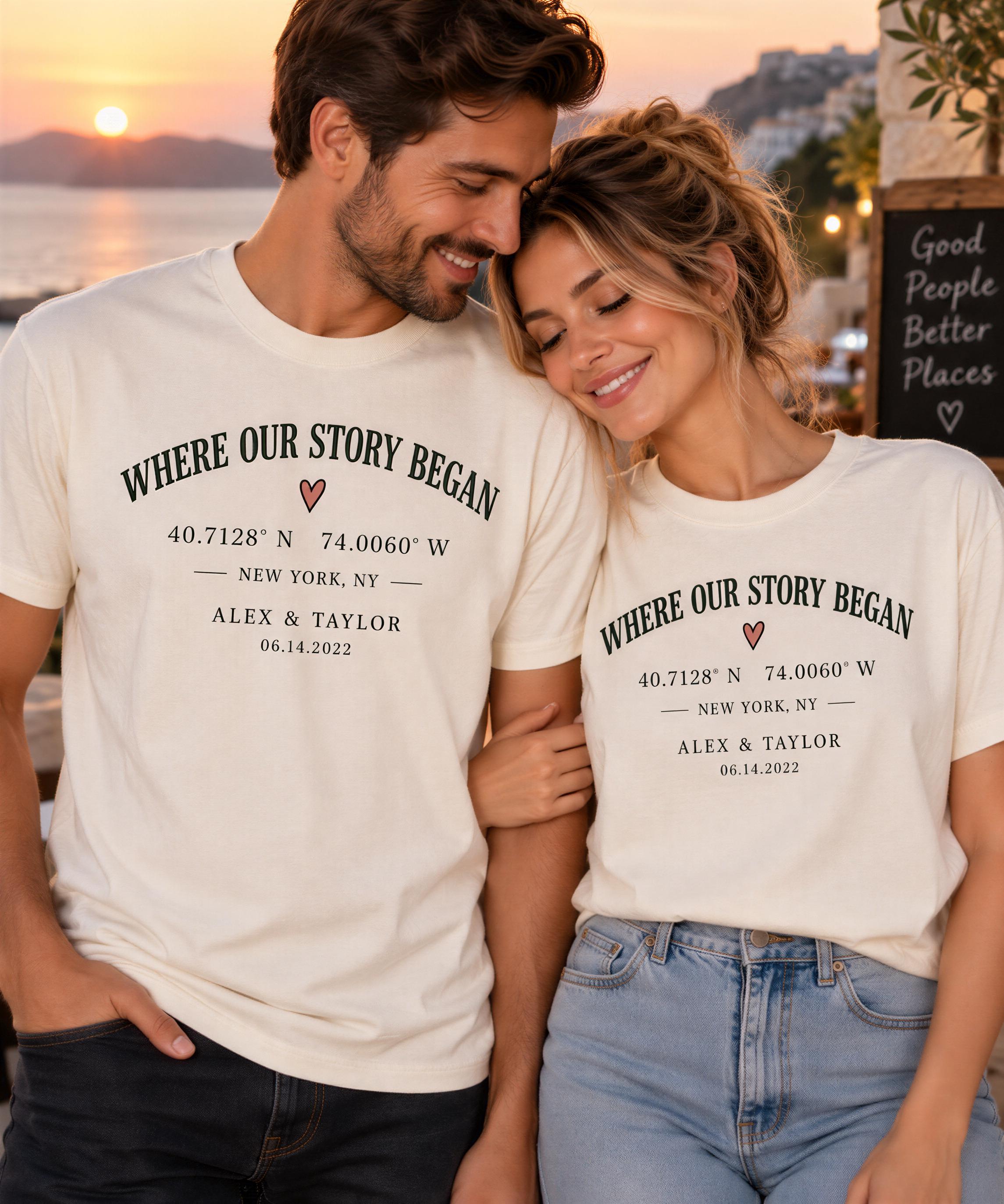 A man and a woman standing close together, smiling and embracing each other. They are wearing matching white t-shirts with text that reads "WHERE OUR STORY BEGINS" and "40.71226° N 74.00060° W".