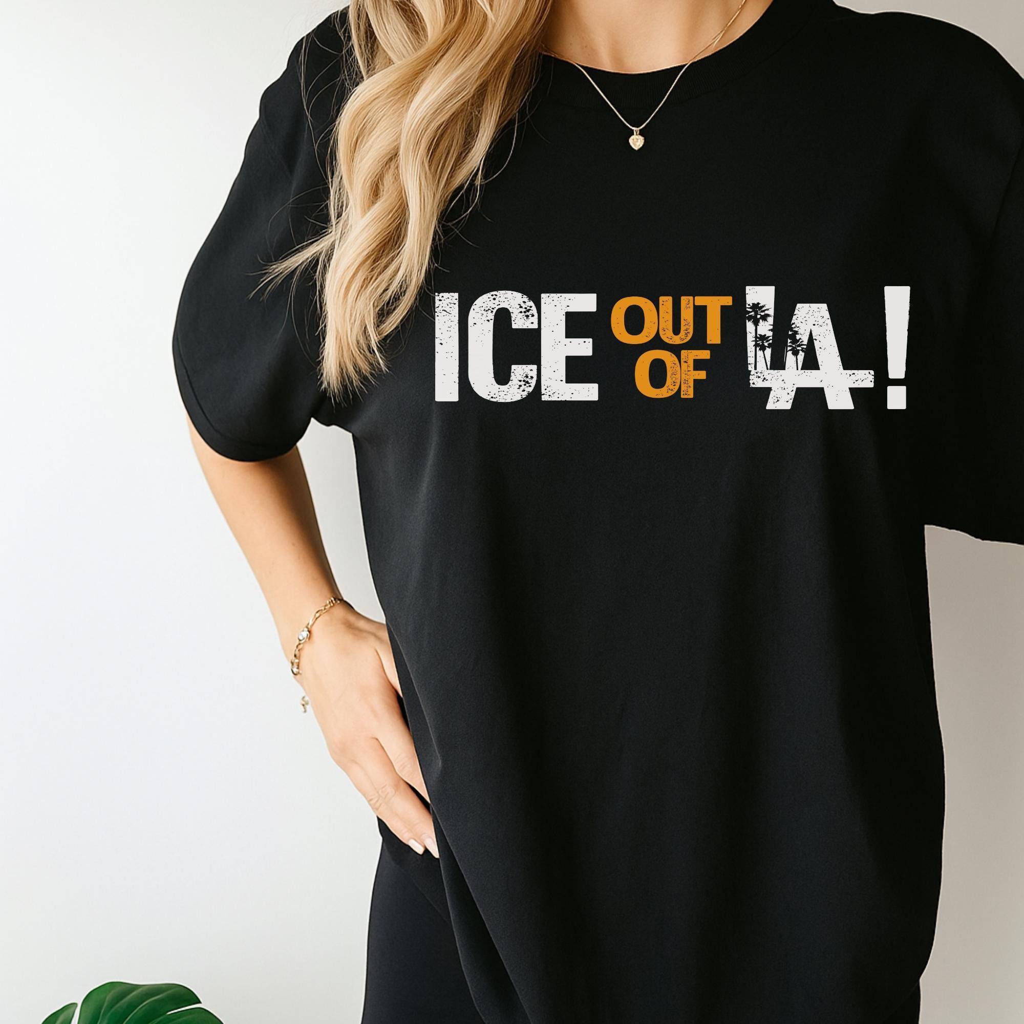 A person wearing a black t-shirt with the text "ICE OUT OF L.A!" printed on it.