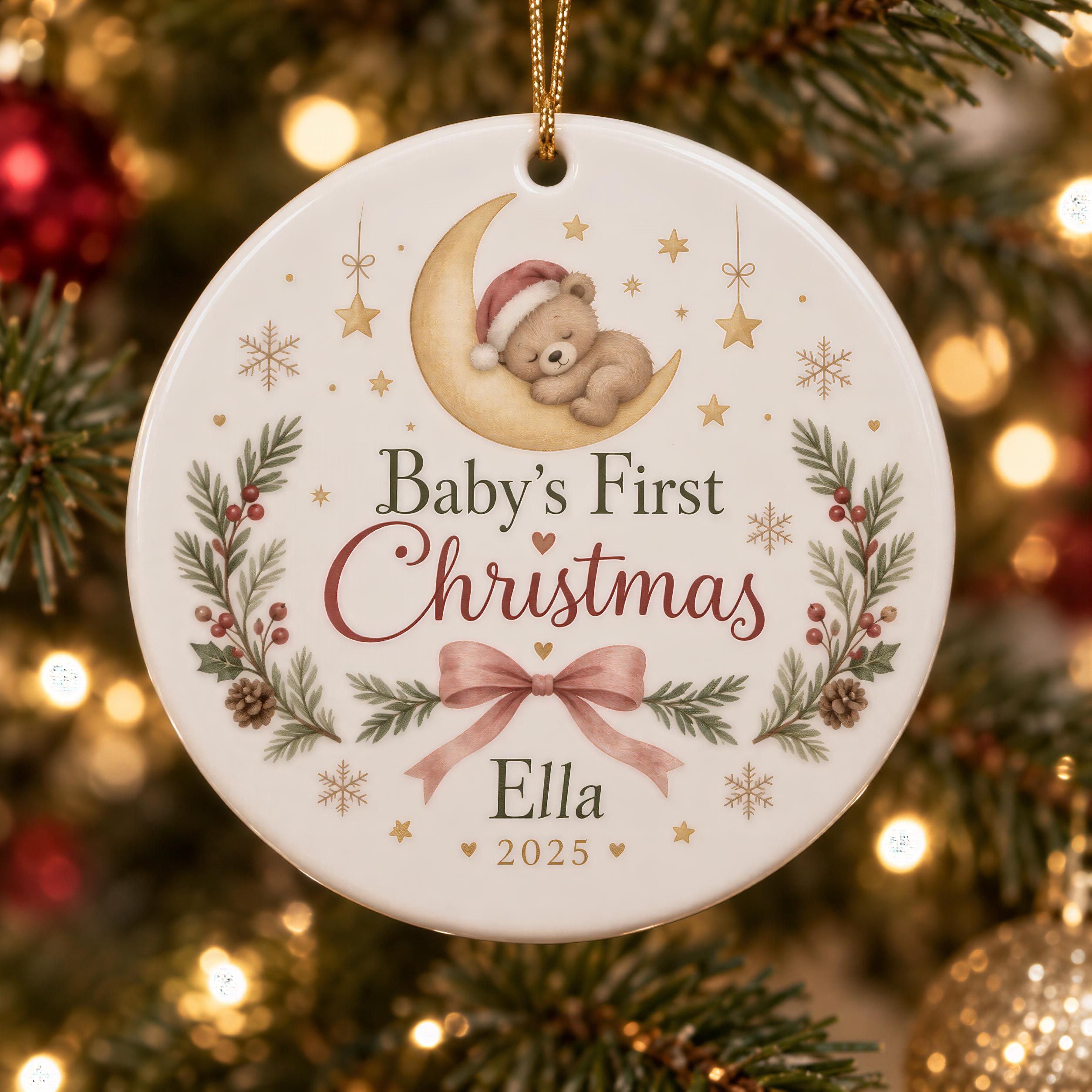 A white ornament with a teddy bear on a crescent moon, surrounded by holiday decorations and the text "Baby's First Christmas Ella 2020".