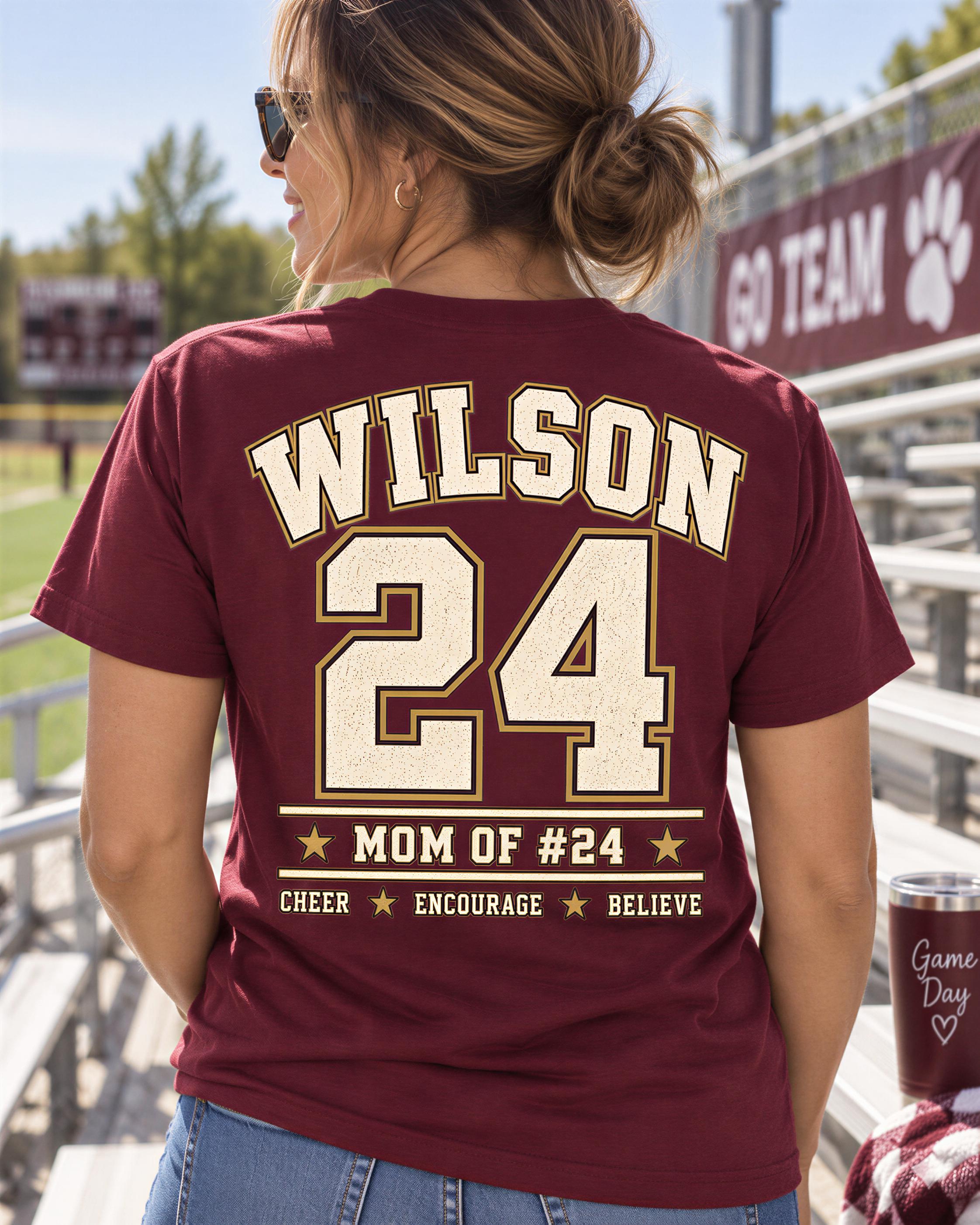 A woman wearing a maroon t-shirt with the name 'WILSON' and the number '24' printed on it, standing in front of a stadium seating area.