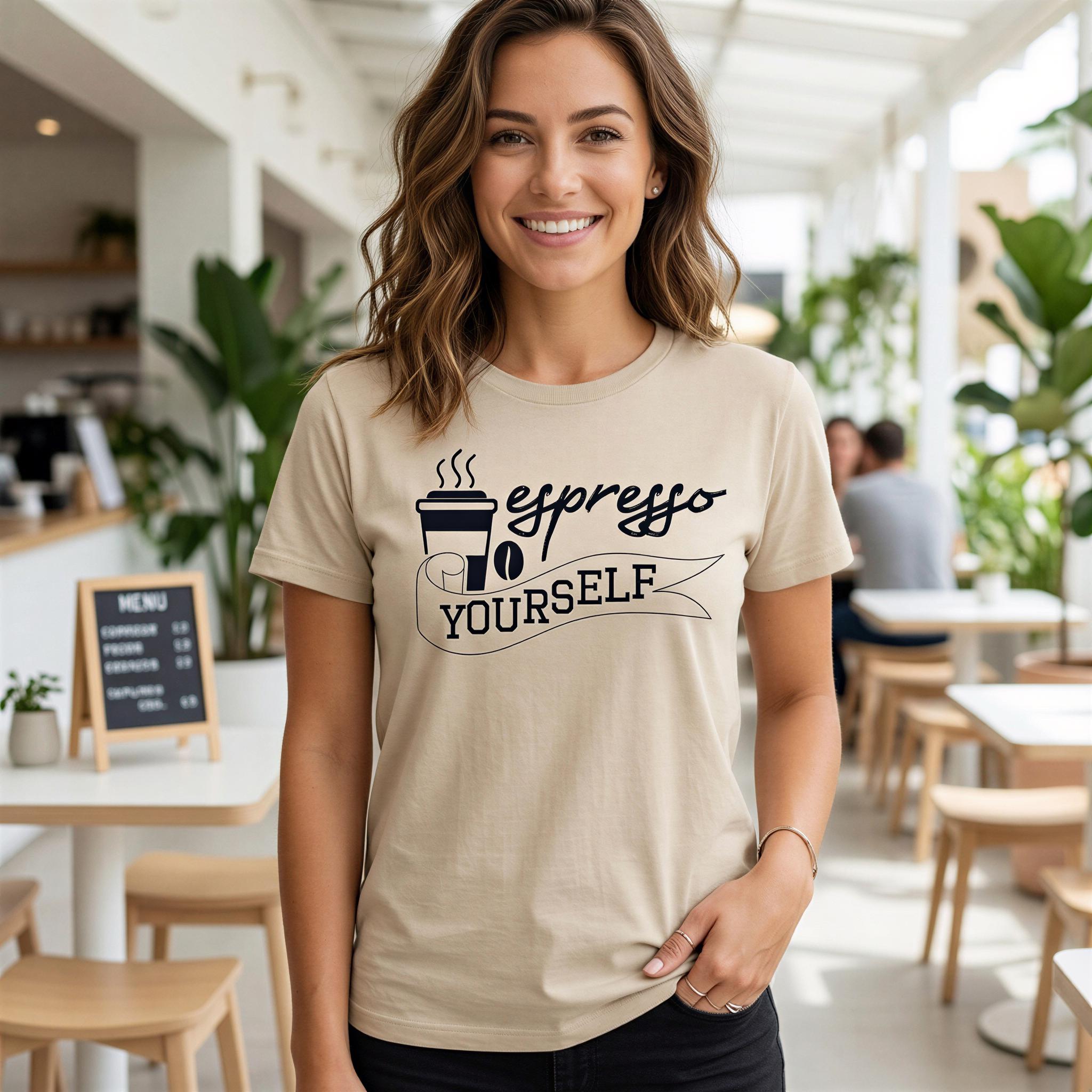 A smiling woman wearing a beige t-shirt with the text "Espresso Yourself" printed on it, standing in a coffee shop or cafe with plants and tables visible in the background.