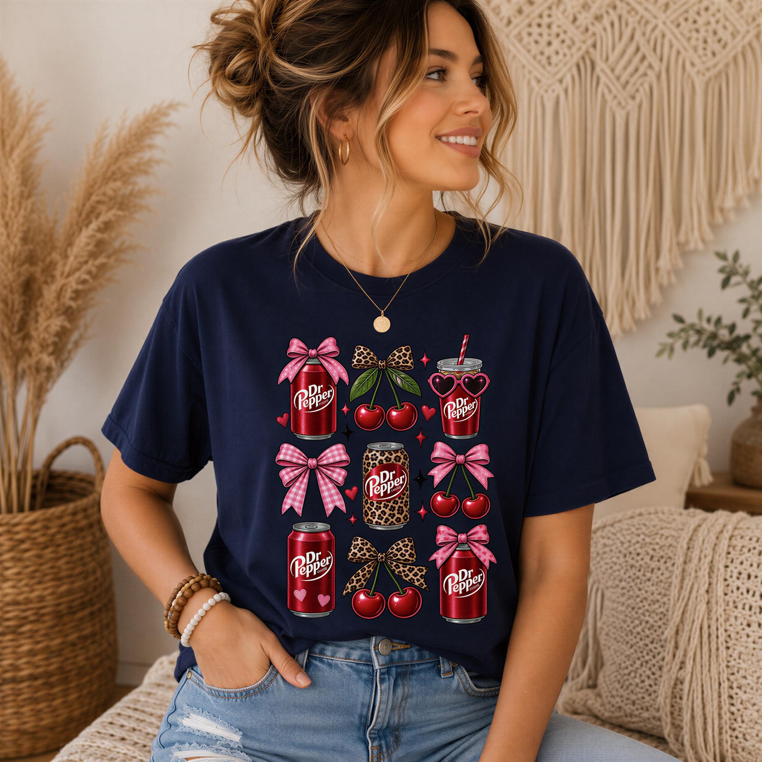 A woman wearing a navy blue t-shirt with a graphic design of various Dr Pepper products, including cans, cherries, and bows, smiling and looking to the side.