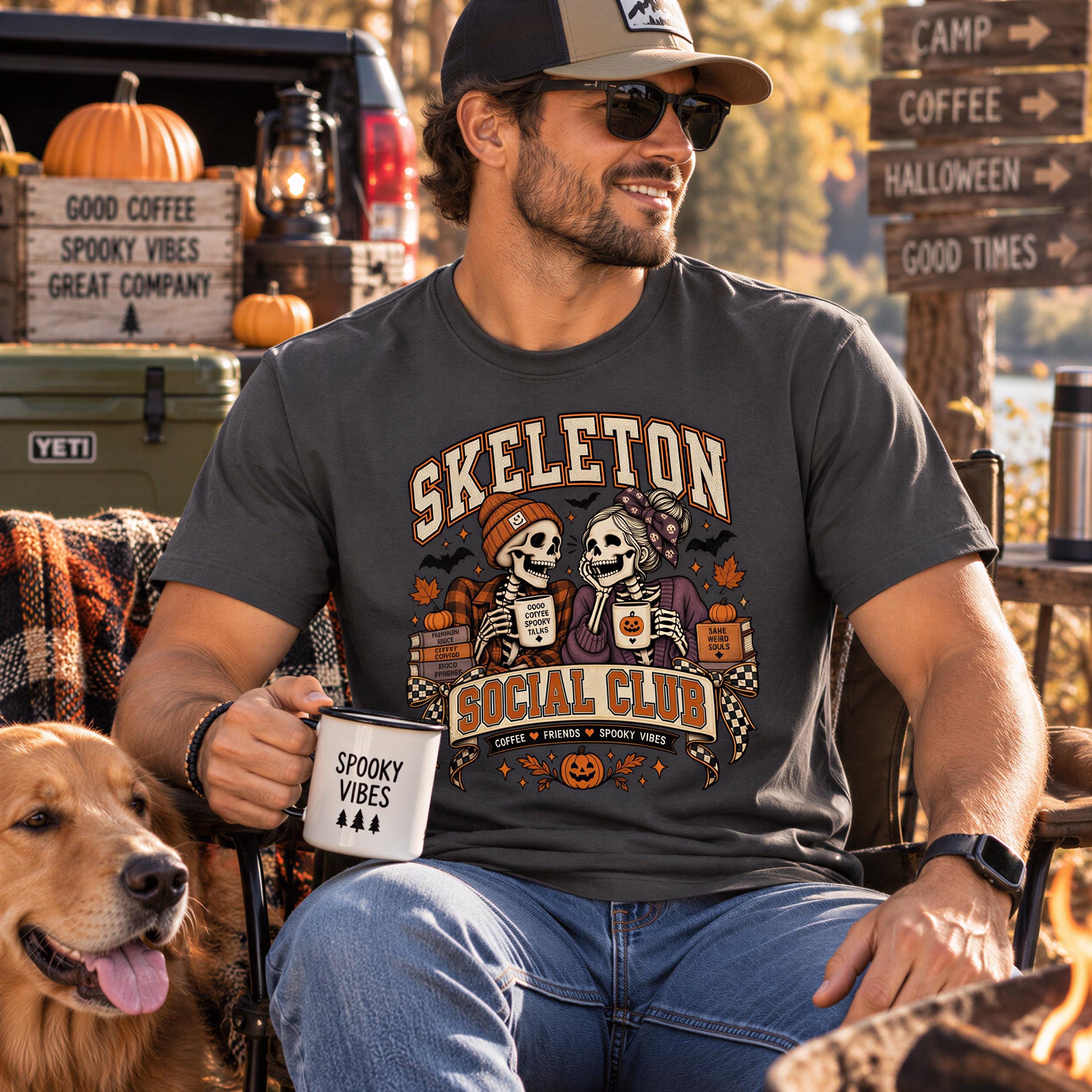 A man wearing a Skeleton t-shirt and sunglasses is sitting outdoors, holding a coffee mug and accompanied by a dog.