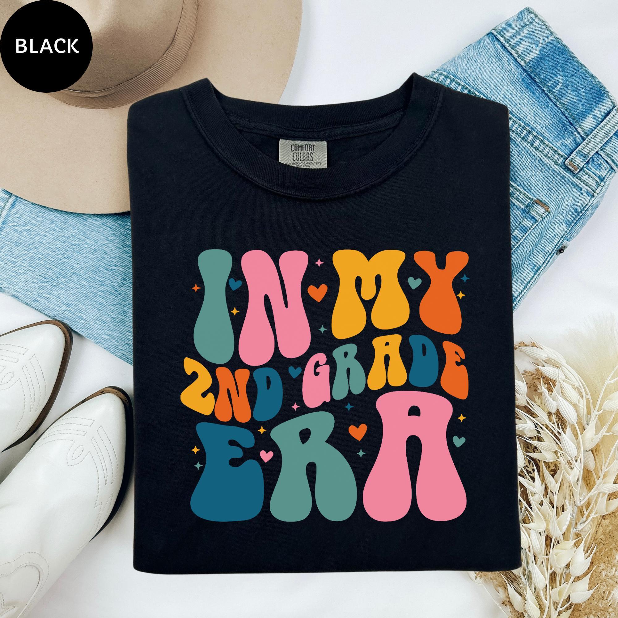 a black t-shirt with a colorful graphic design, a pair of white cowboy boots, and some denim jeans.