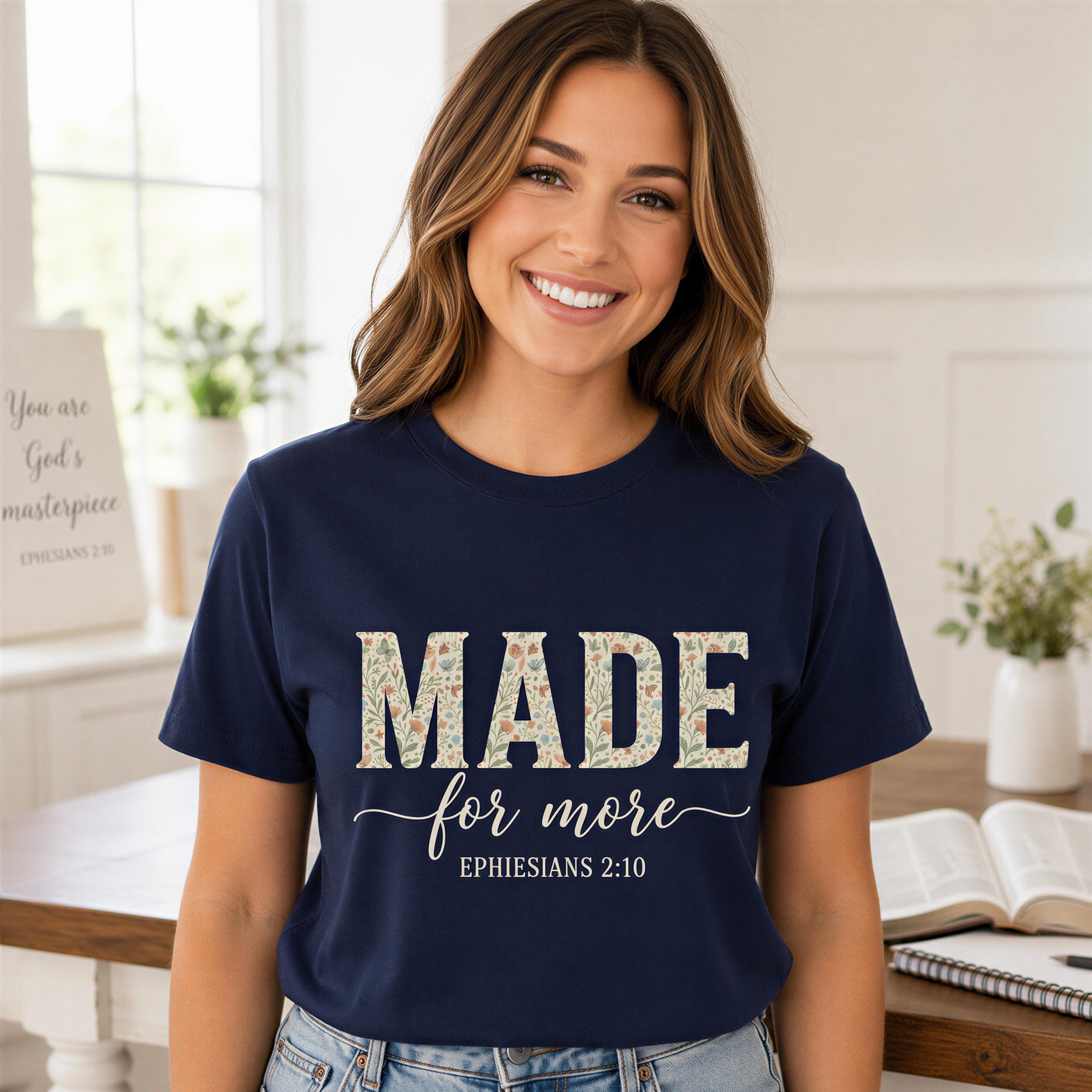 A woman wearing a navy blue t-shirt with the text "MADE for more" and "EPHESIANS 2:10" printed on it, smiling at the camera.