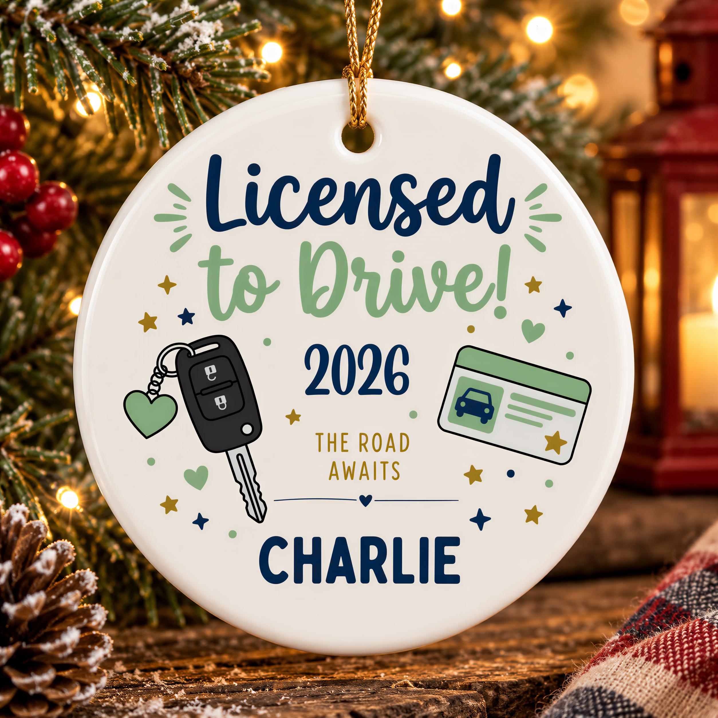 A white ornament with a festive design, featuring a license to drive symbol, a car key, and a license plate, along with the text "LICENSED to DRIVE! 2026 THE ROAD AWAITS CHARLIE".