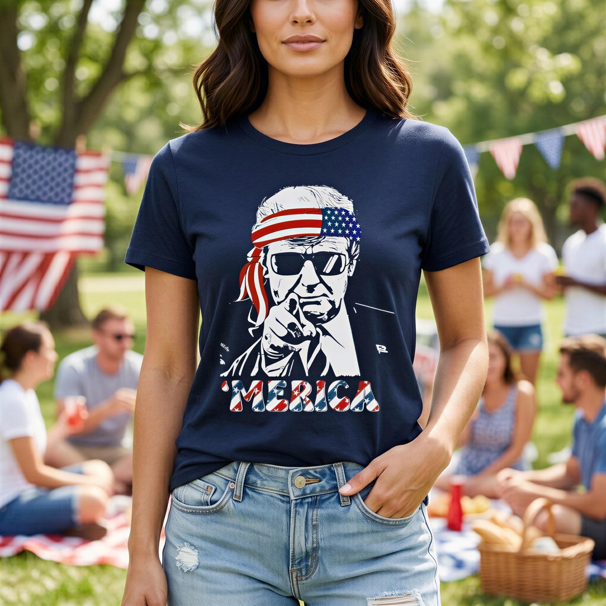 A woman wearing a navy blue t-shirt with a graphic of a man wearing sunglasses and an American flag bandana, standing in a park with other people in the background.