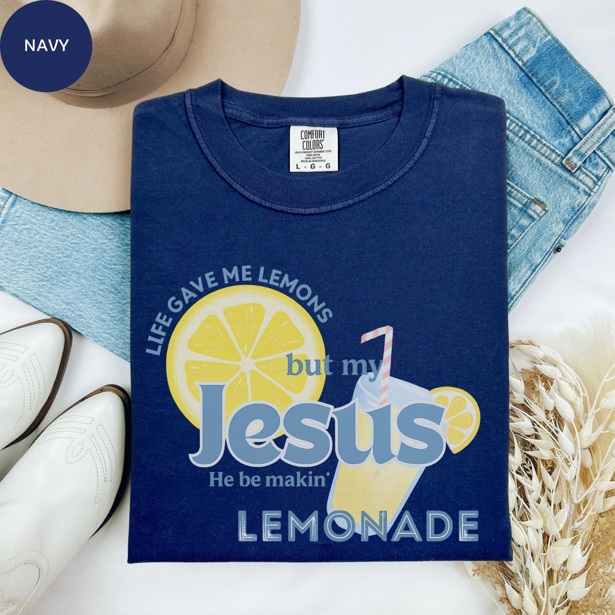 Navy blue t-shirt with a graphic design, jeans, a hat, and some flowers on a white background.