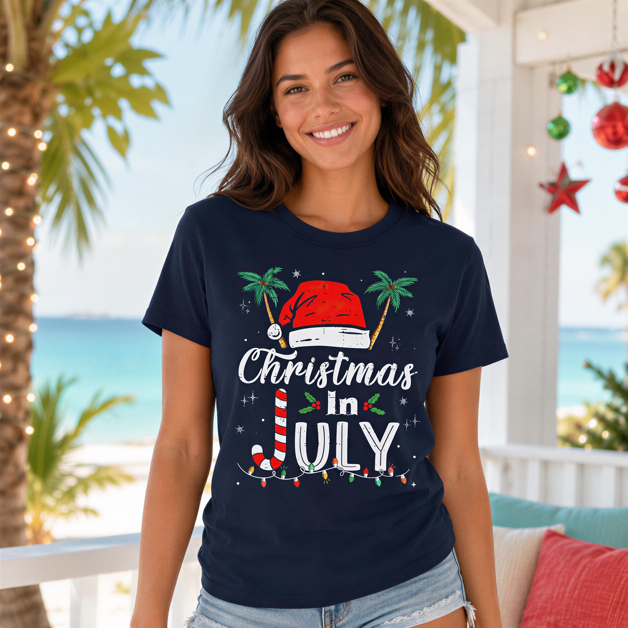 A smiling woman wearing a navy blue t-shirt with a Christmas-themed design, including a Santa hat, palm trees, and the text "Christmas in July".