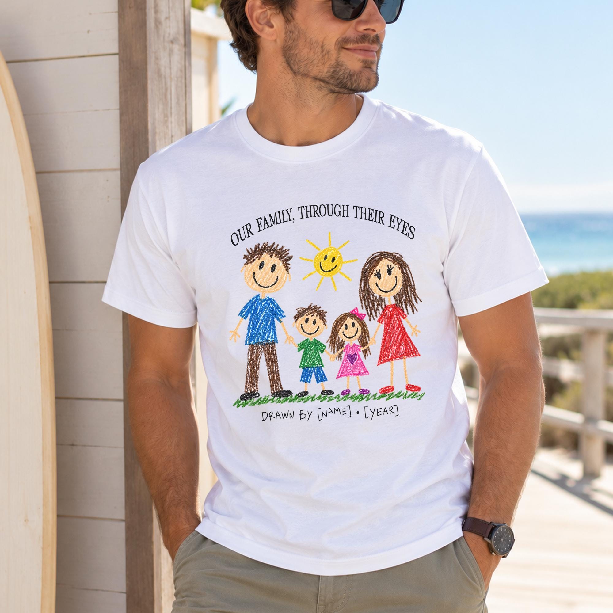 A man wearing a white t-shirt with a drawing of a family and the text "Our family, through their eyes" printed on it.