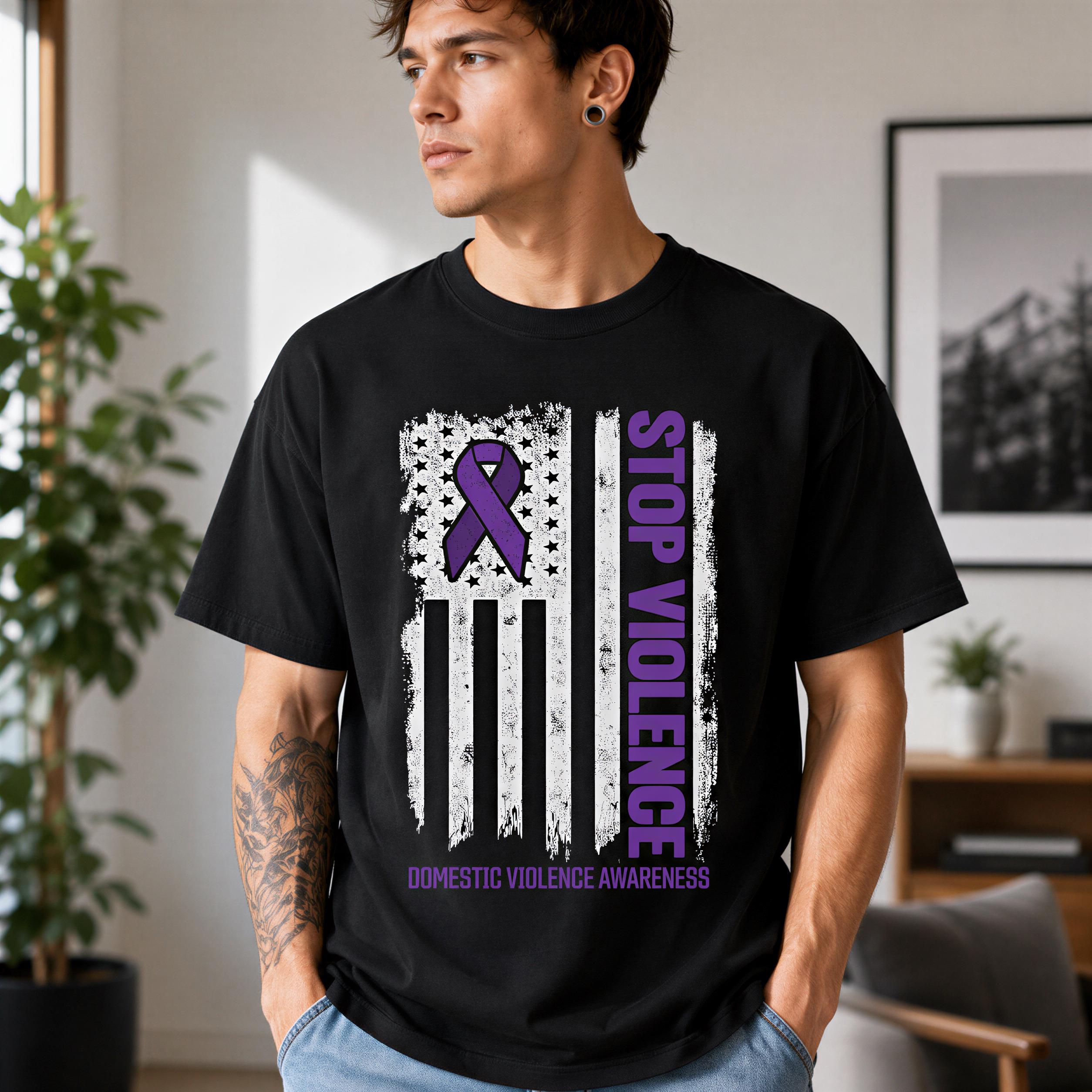 A man wearing a black t-shirt with a graphic design featuring a purple ribbon and an American flag, along with the text "STOP VIOLENCE" and "DOMESTIC VIOLENCE AWARENESS".