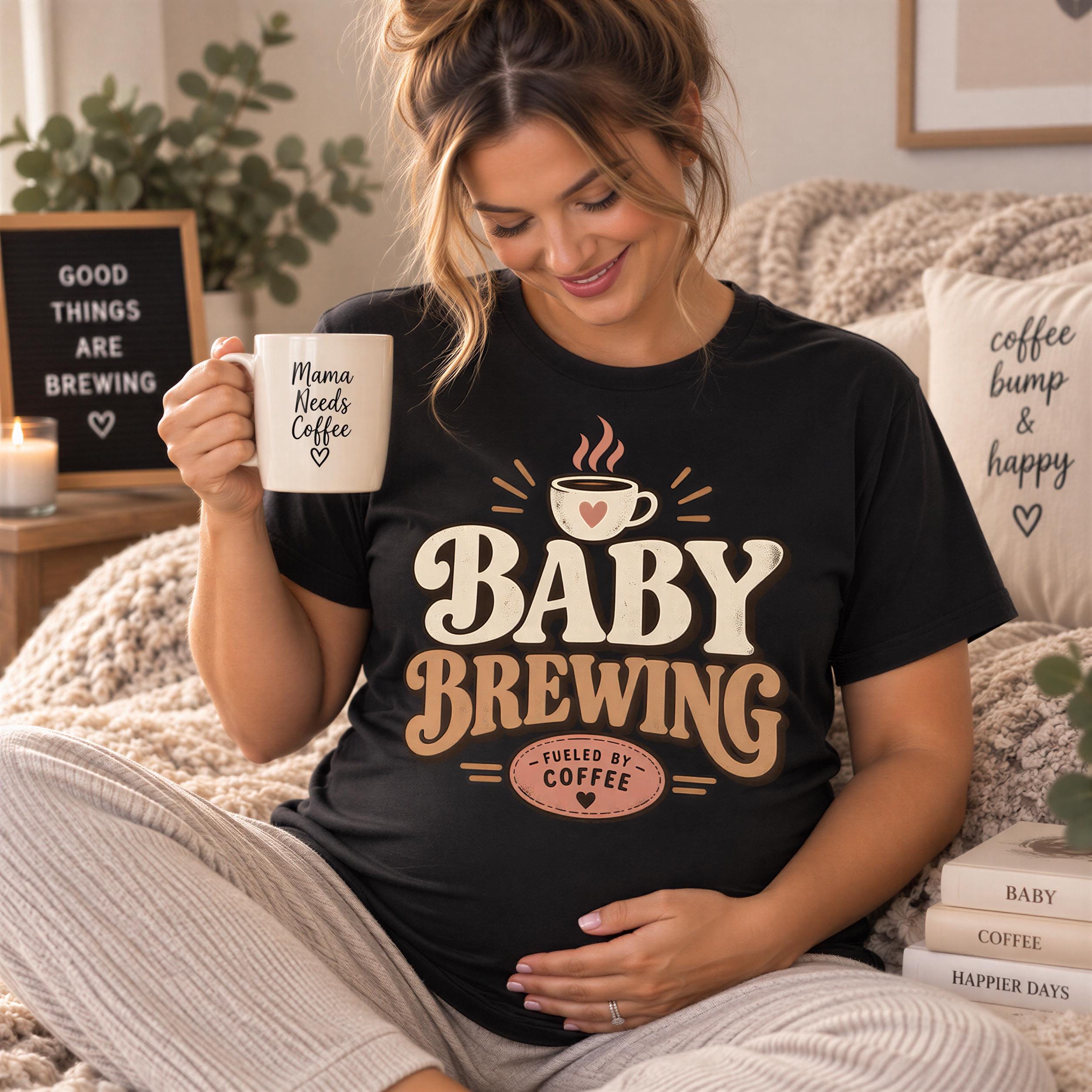 A pregnant woman is sitting on a couch, holding a coffee mug and smiling. She is wearing a black t-shirt with a design that says "BABY BREWING" and "Mama needs coffee".