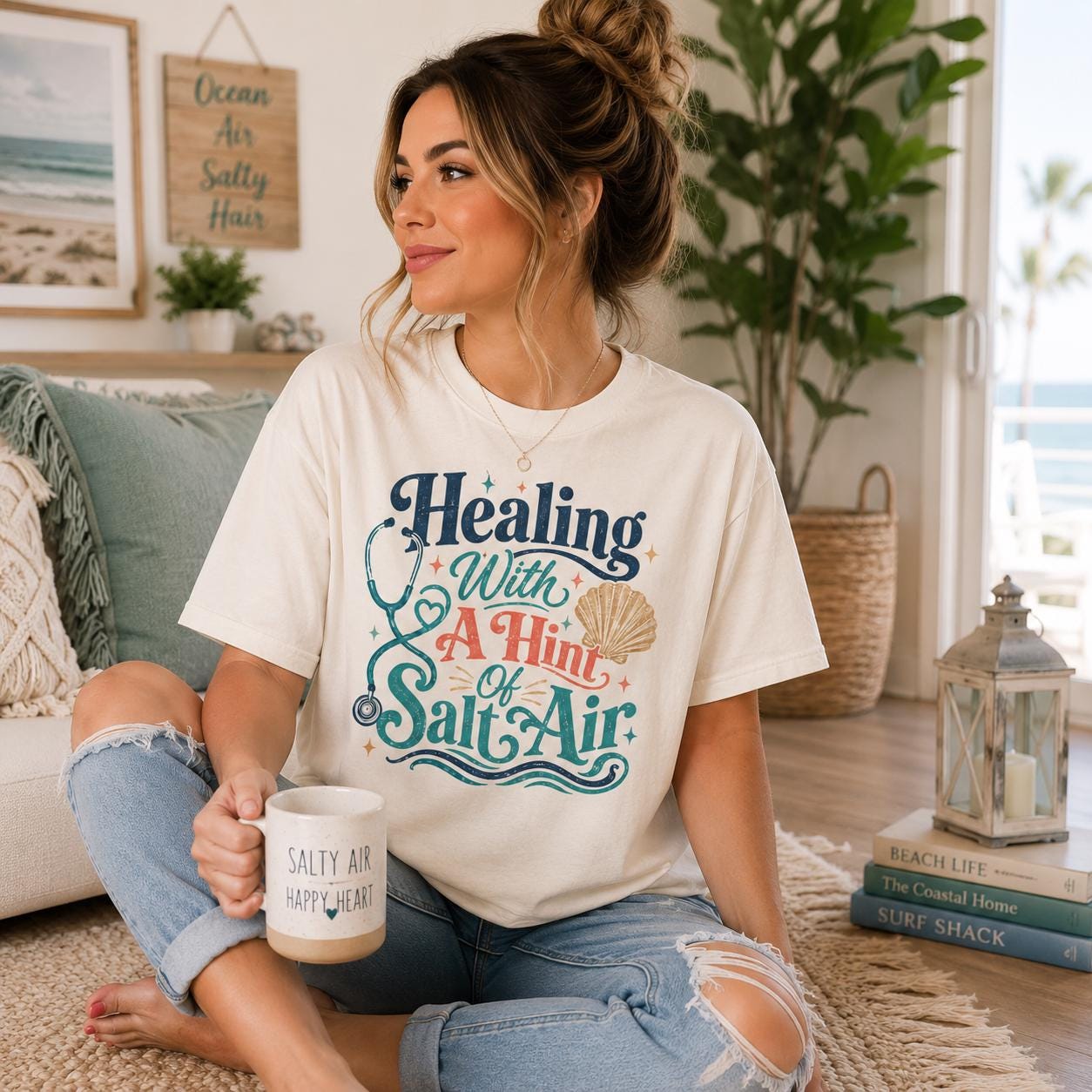 A woman sitting on the floor, holding a coffee mug and wearing a t-shirt with a colorful graphic design.