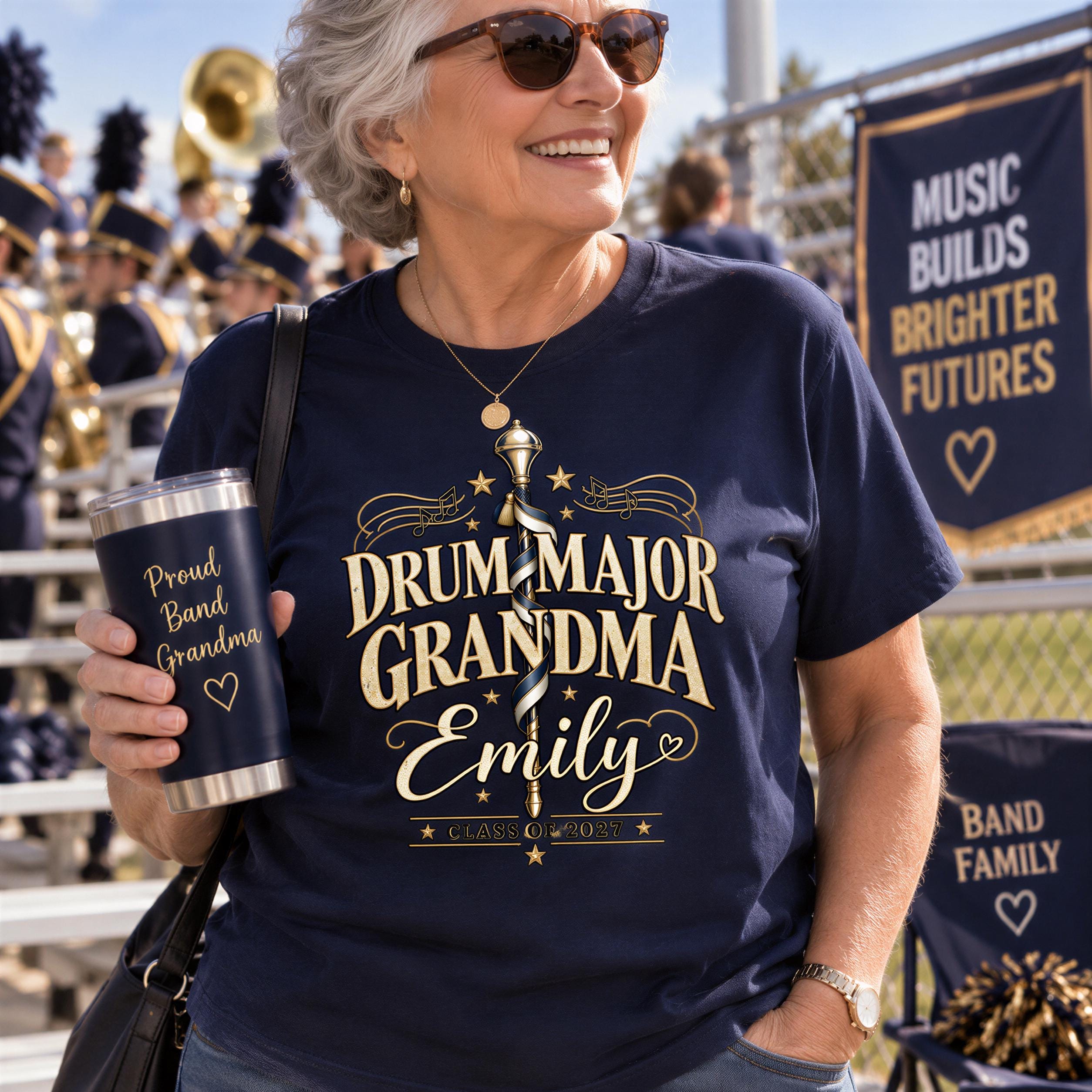 A woman wearing a navy blue t-shirt with gold text and a gold design, smiling and holding a silver cup with text on it.