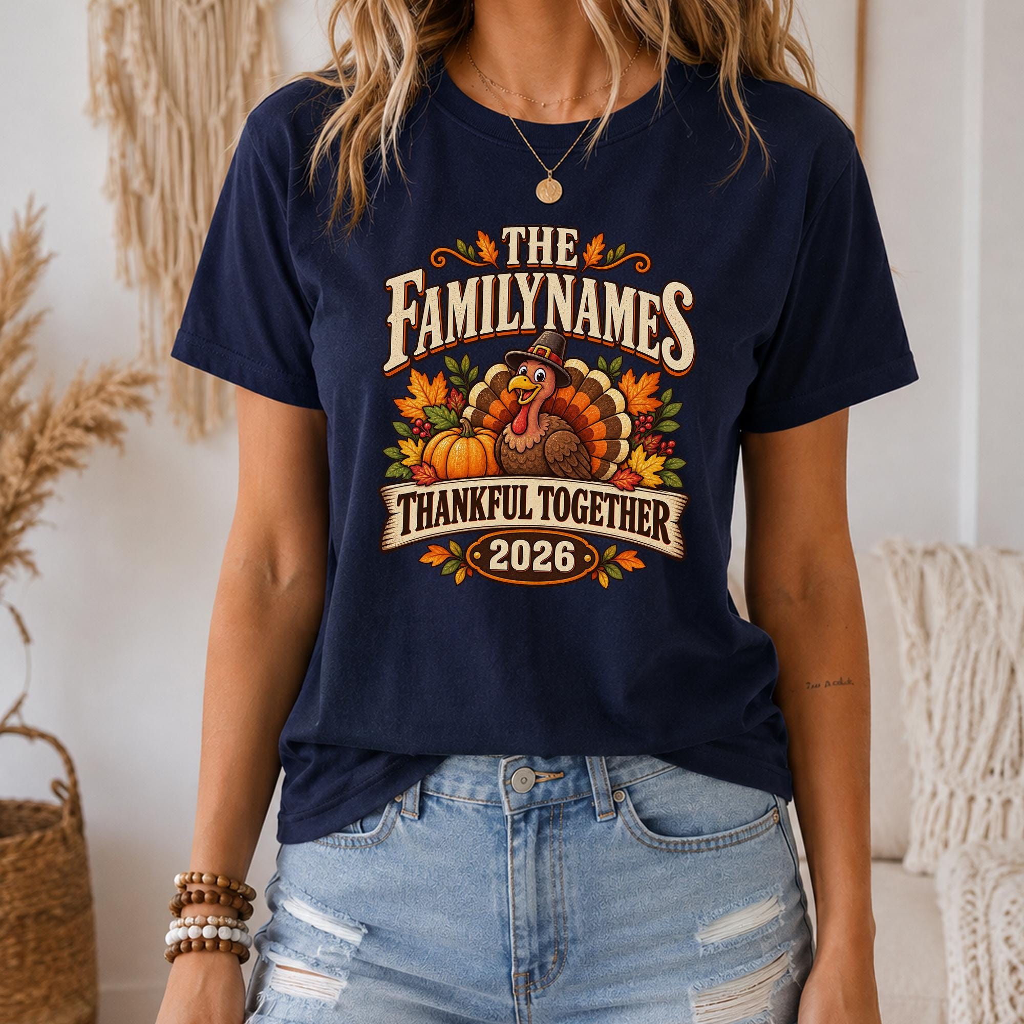 A woman wearing a navy blue t-shirt with a graphic design featuring a turkey, pumpkins, and the text "The Family Names Thankful Together 2016".