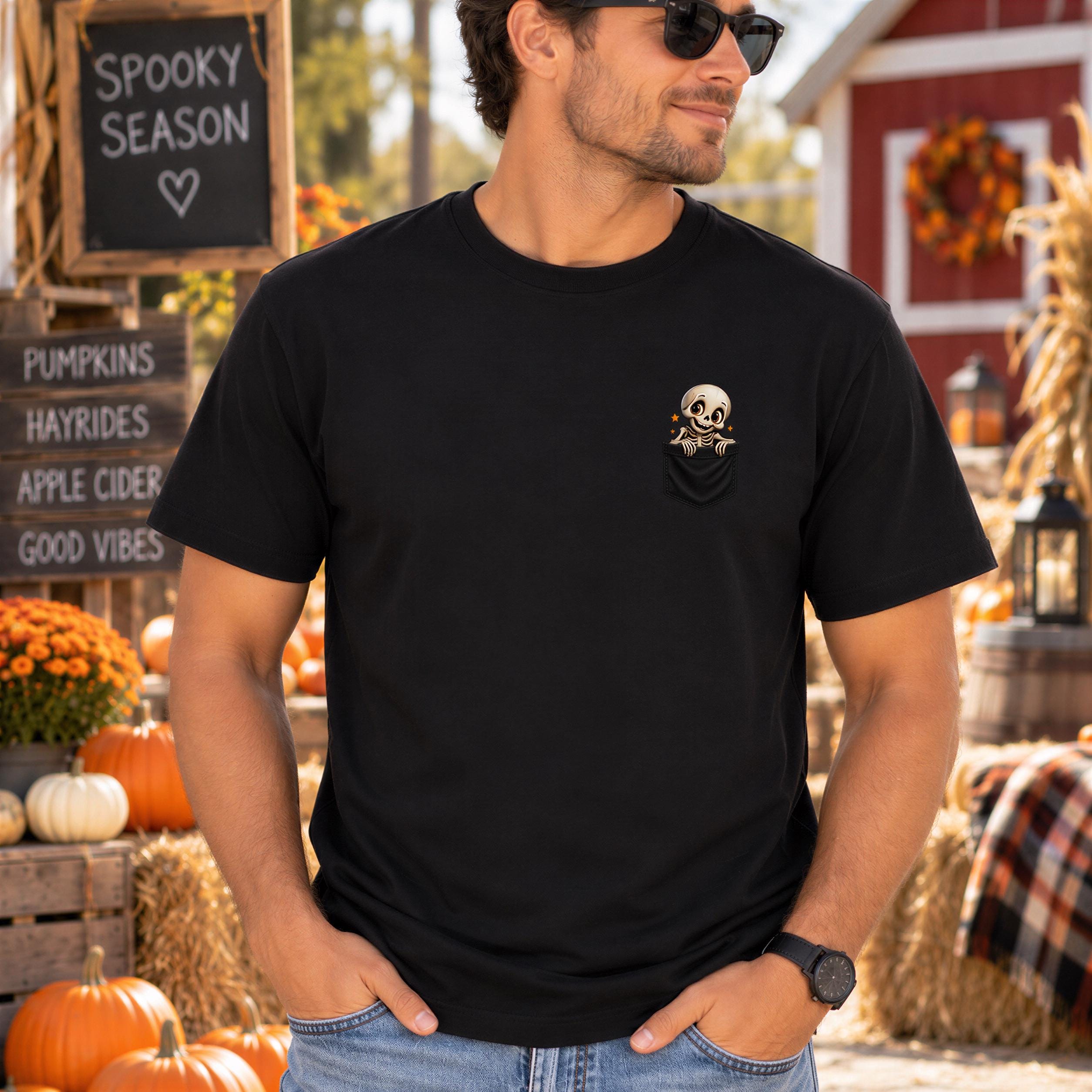 A man wearing a black t-shirt with a skull design stands in front of a Halloween-themed display, including pumpkins, hay bales, and a sign that says "Spooky Season".