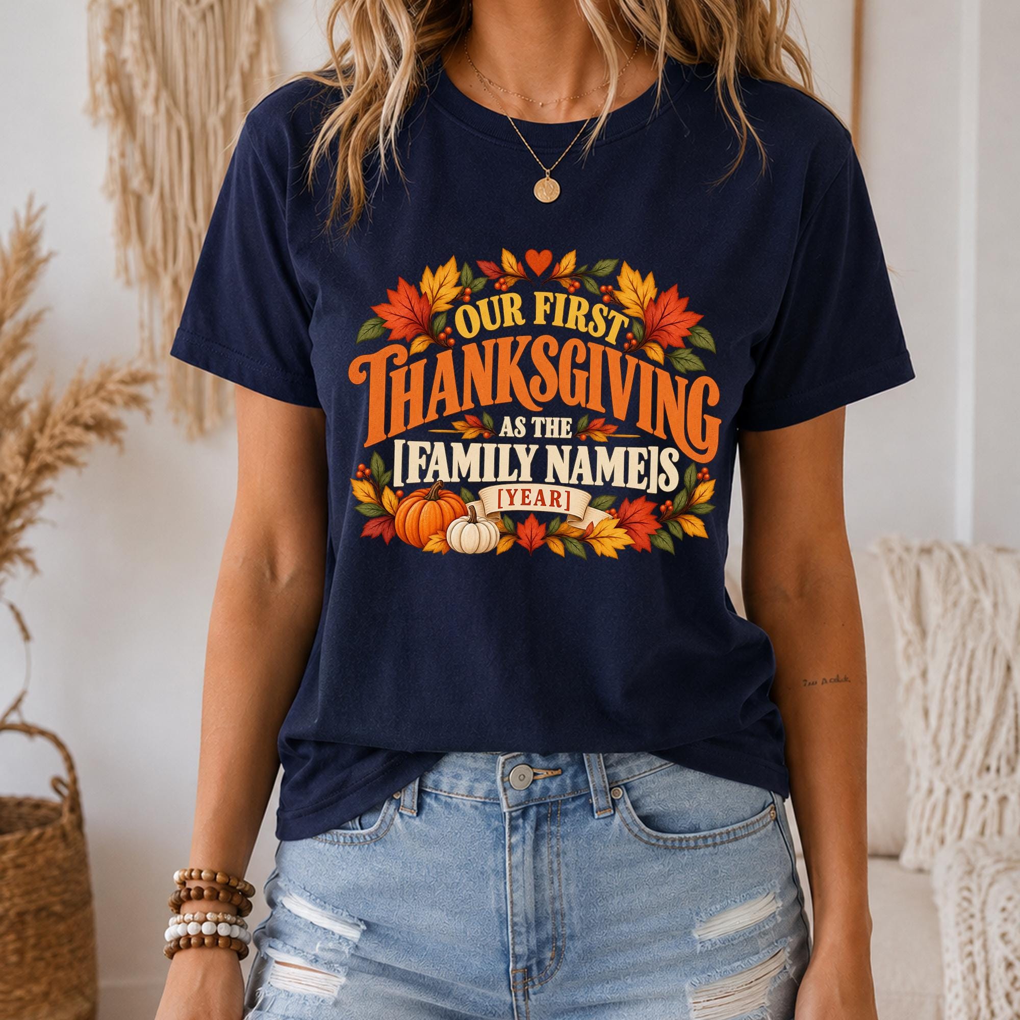A woman wearing a navy blue t-shirt with a graphic design that says "Our first Thanksgiving as the family name's 1 year" and includes autumn leaves and pumpkins.