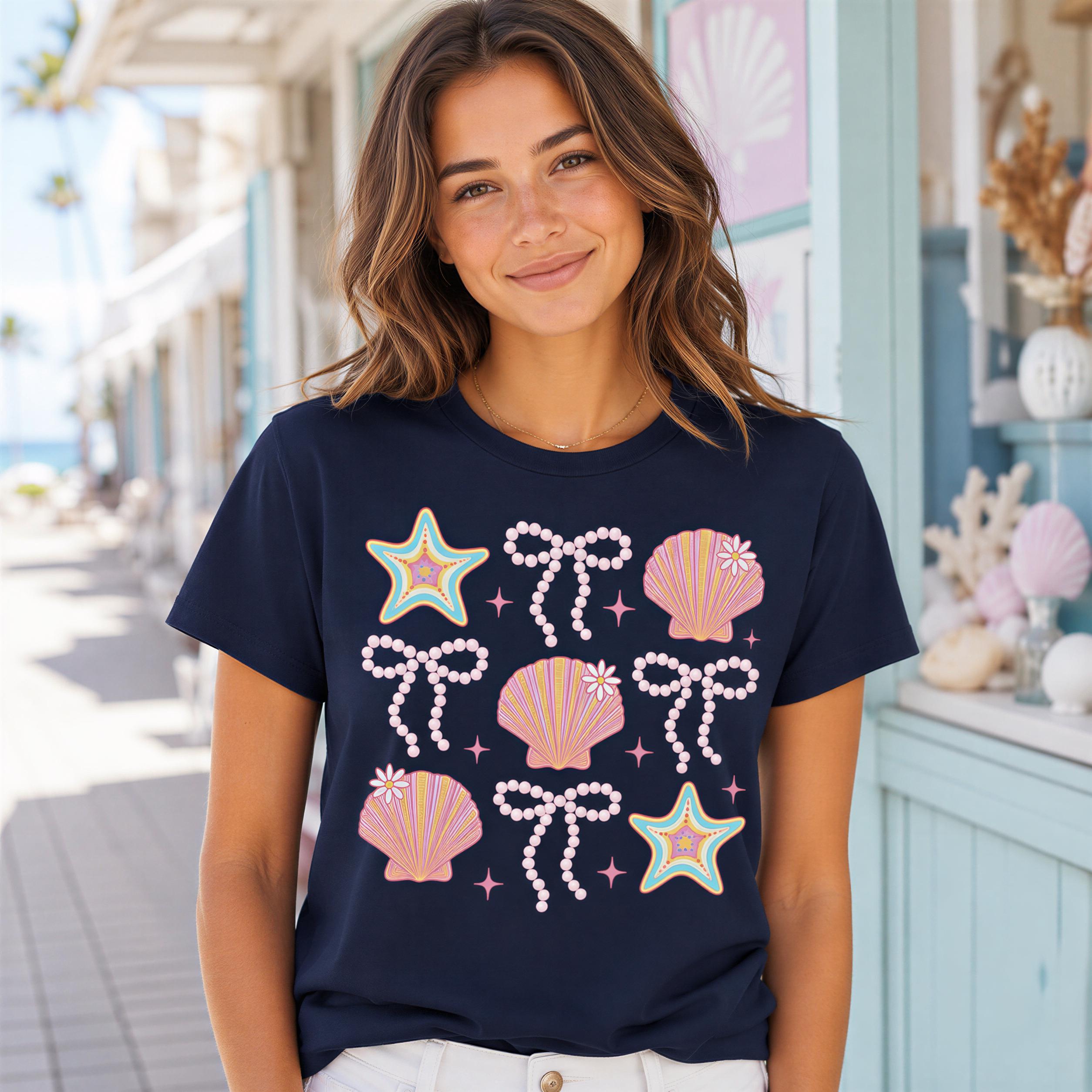 A woman wearing a navy blue t-shirt with a design of seashells, stars, and bows, standing in front of a blue building with palm trees.