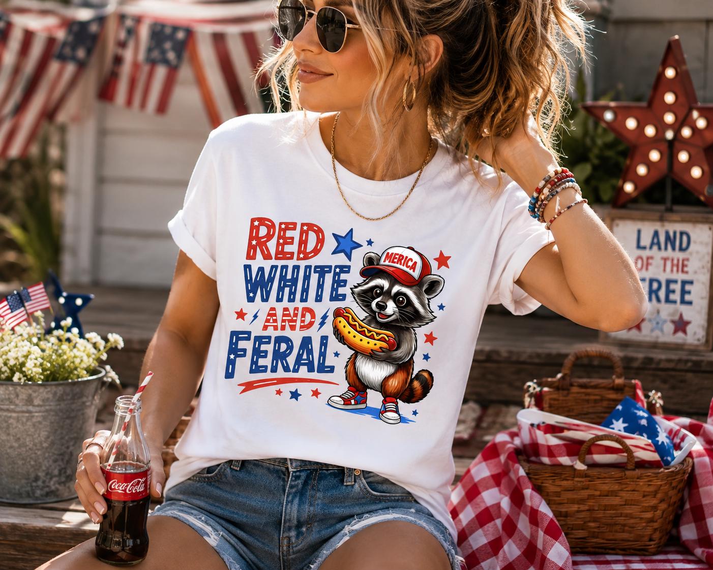 A woman wearing a white t-shirt with a raccoon graphic and patriotic text, sitting outdoors with a Coca-Cola bottle in her hand.