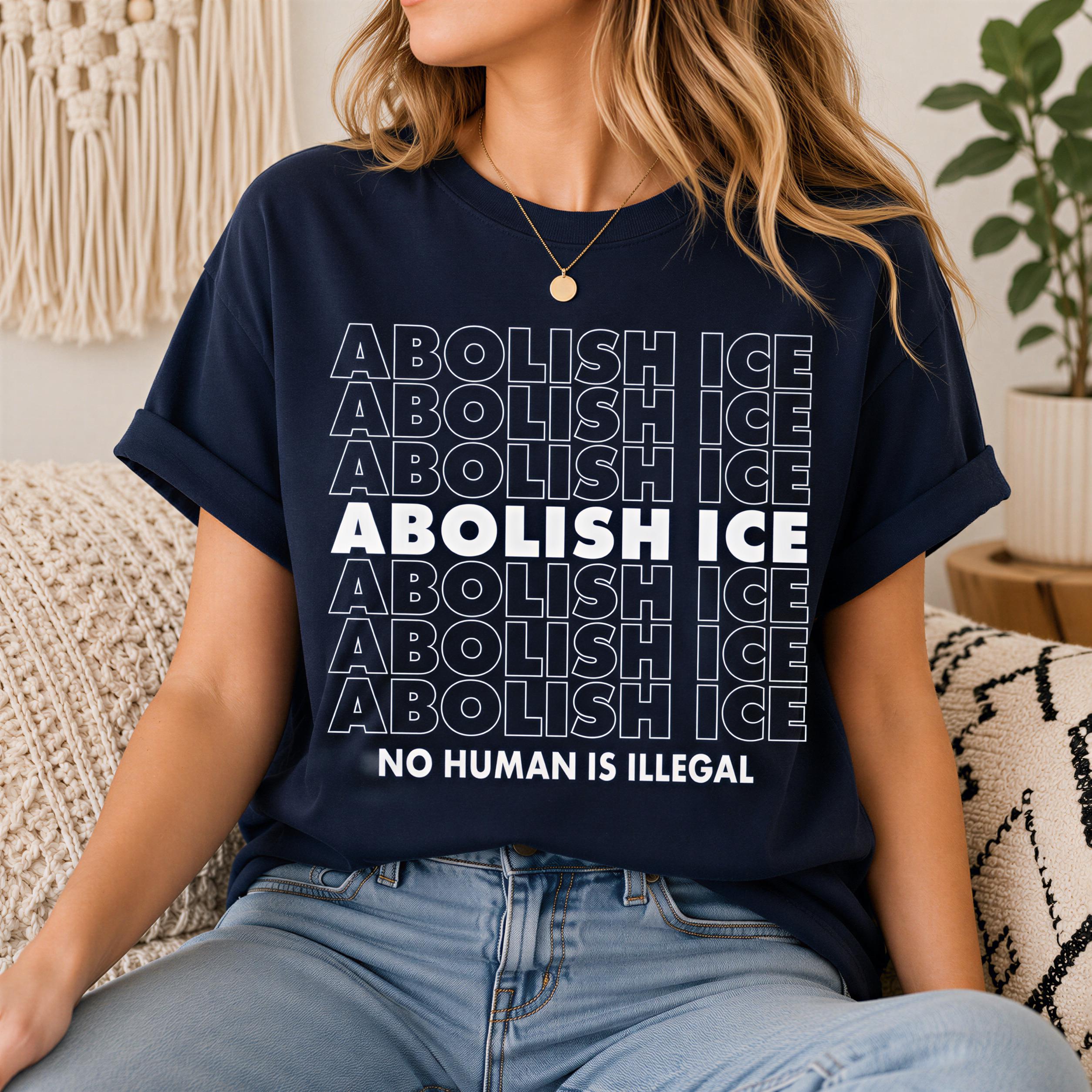 A woman wearing a navy blue t-shirt with the text "AOLISH ICE NO HUMAN IS ILLEGAL" printed on it.