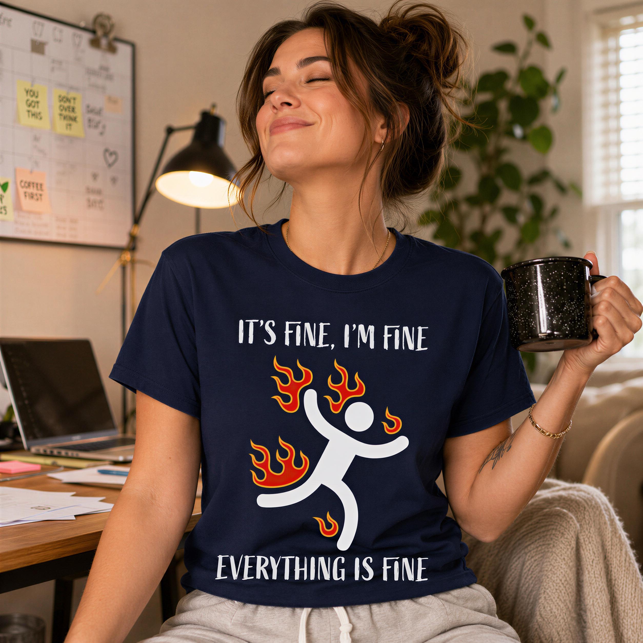 A woman wearing a blue t-shirt with a graphic design and text, sitting in a room with a laptop and plants in the background.