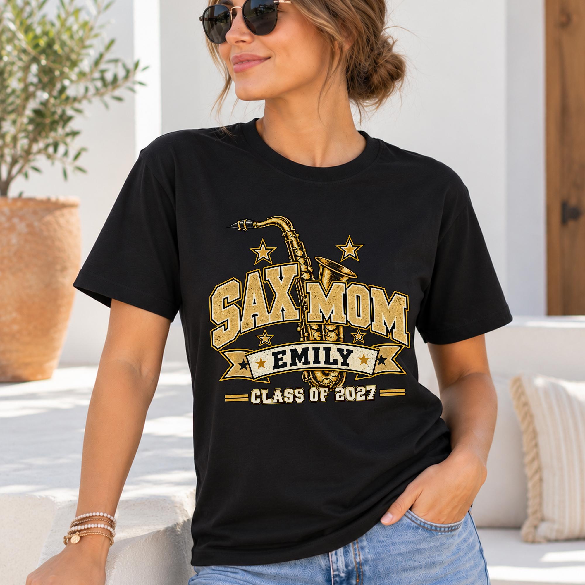 A woman wearing a black t-shirt with a graphic design and text, standing in front of a potted plant.