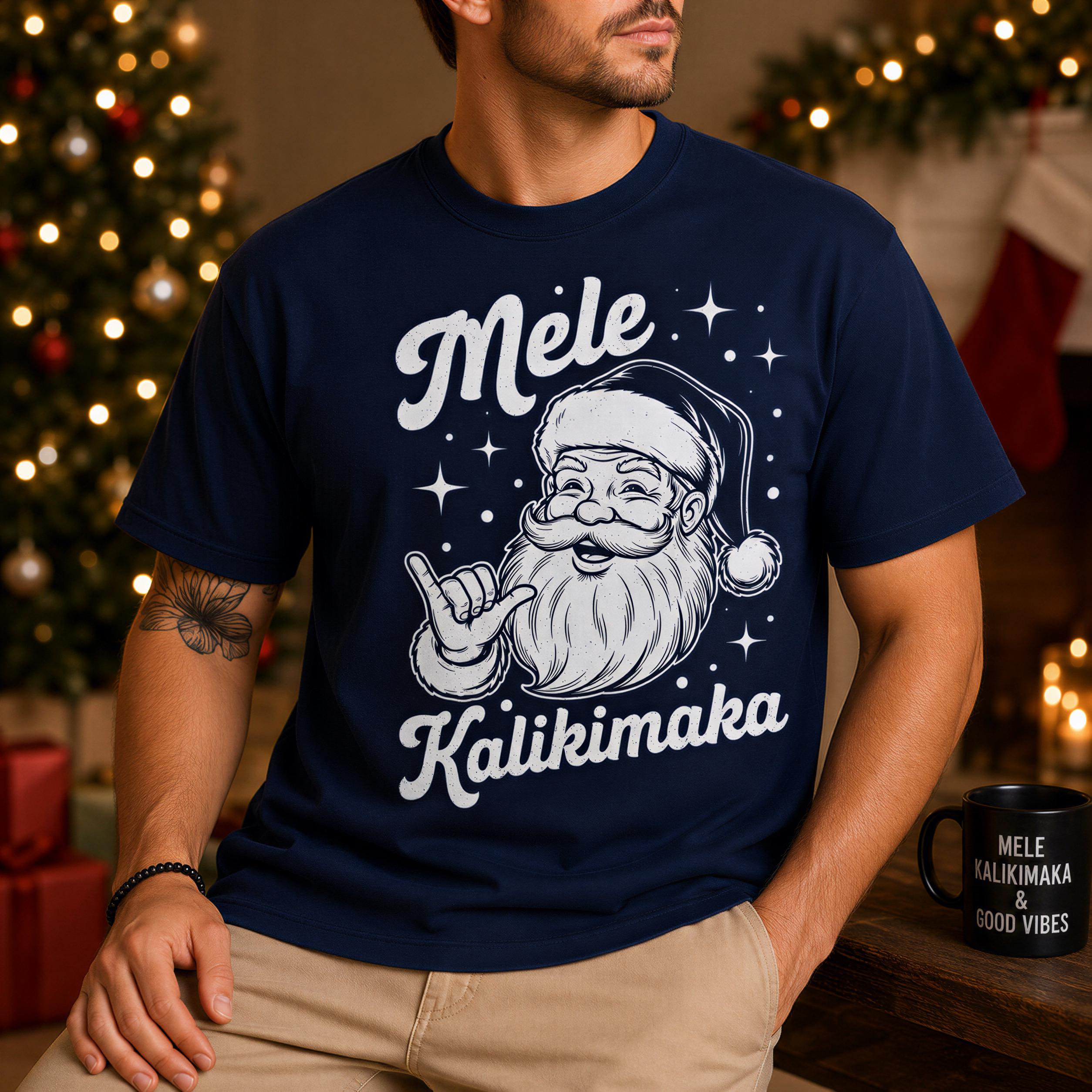 A man wearing a navy blue t-shirt with a graphic of Santa Claus and the text "Mele Kailikimaka" is sitting in front of a Christmas tree.