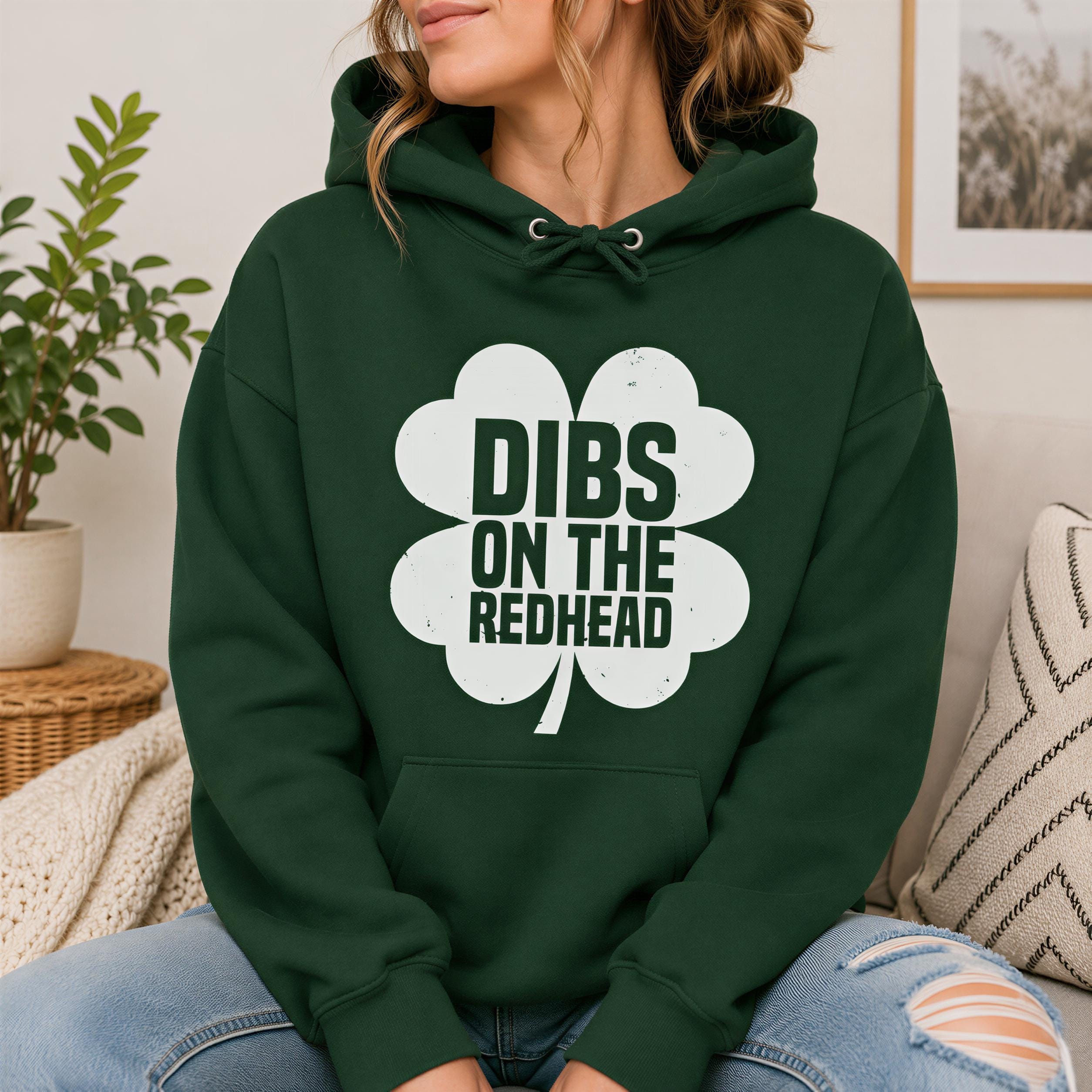 A woman wearing a green hoodie with the text "DIBS ON THE REDHEAD" printed on it.