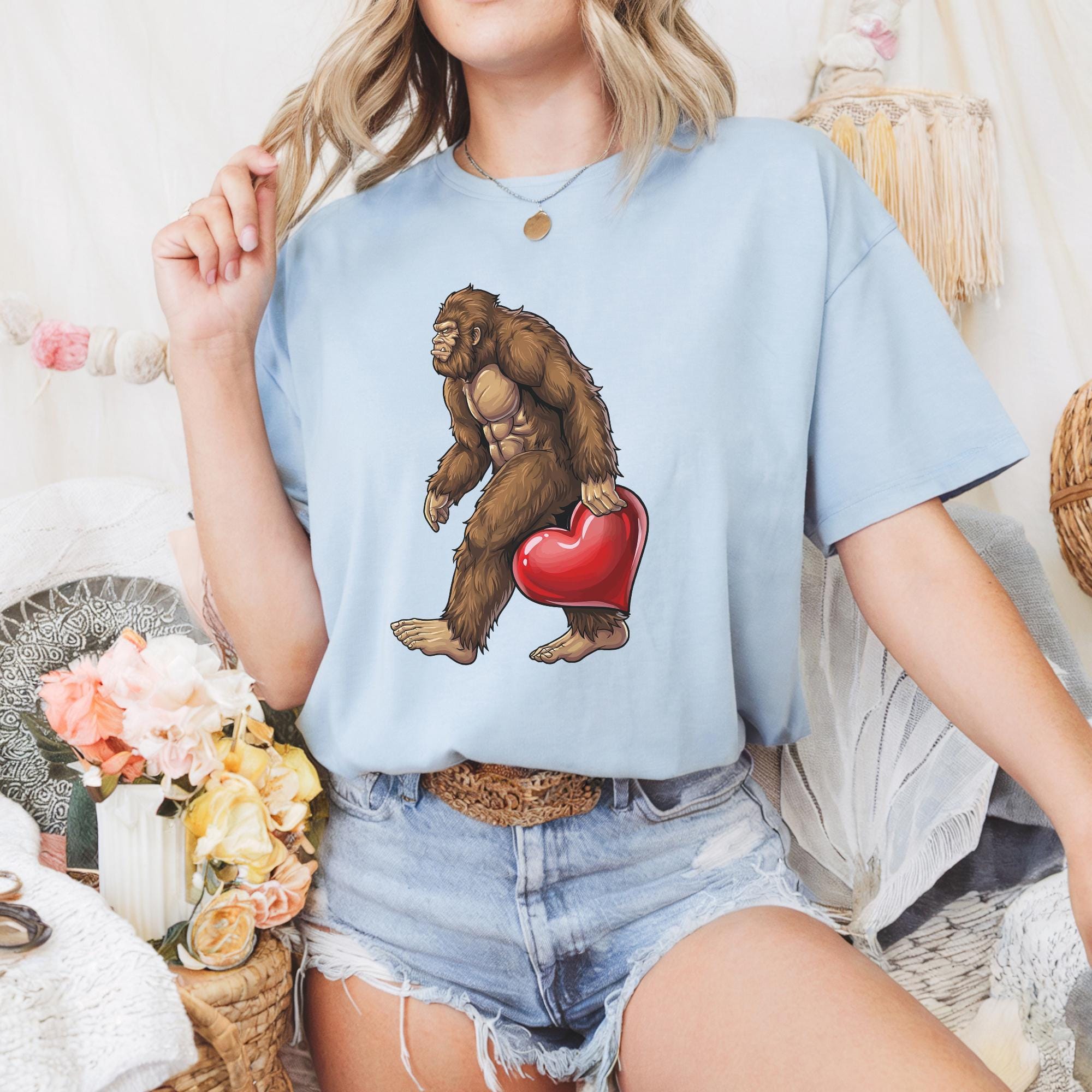 A woman wearing a blue t-shirt with a graphic of a brown gorilla holding a red heart.