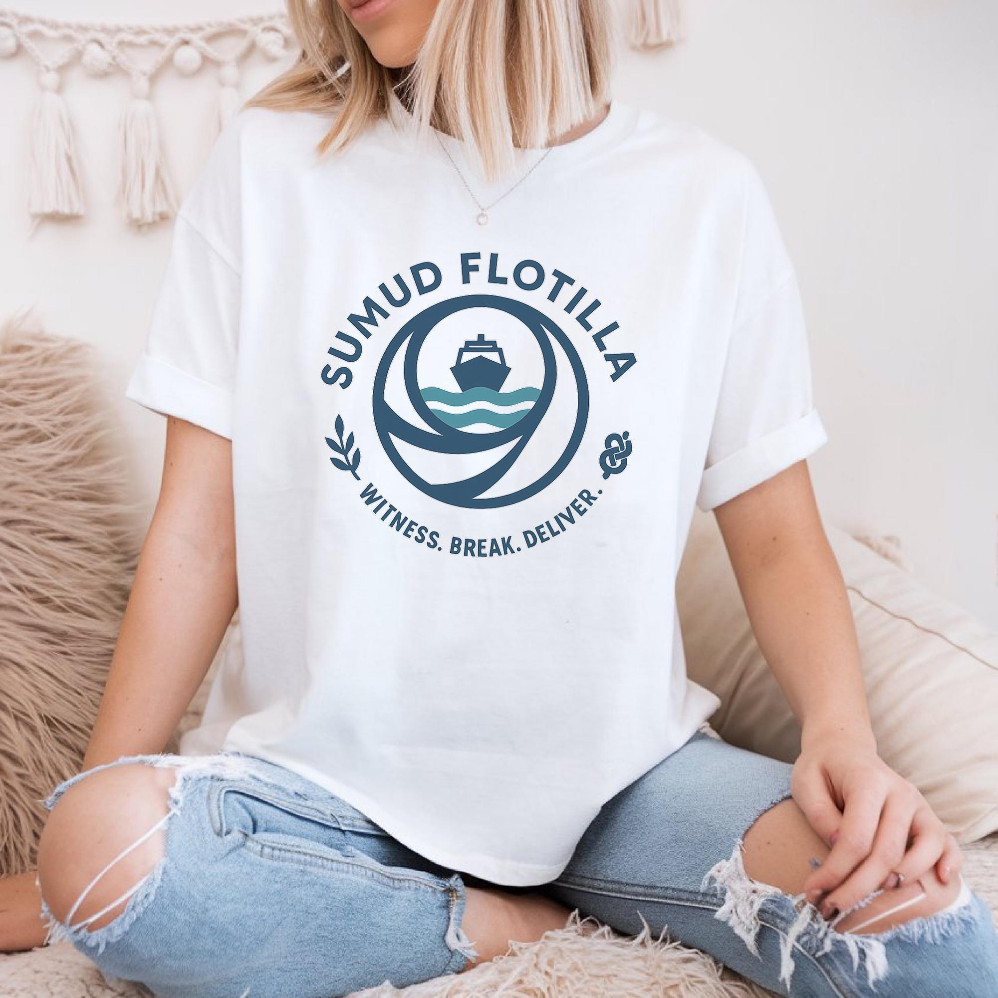 A woman wearing a white t-shirt with a graphic design and text, sitting on a couch.