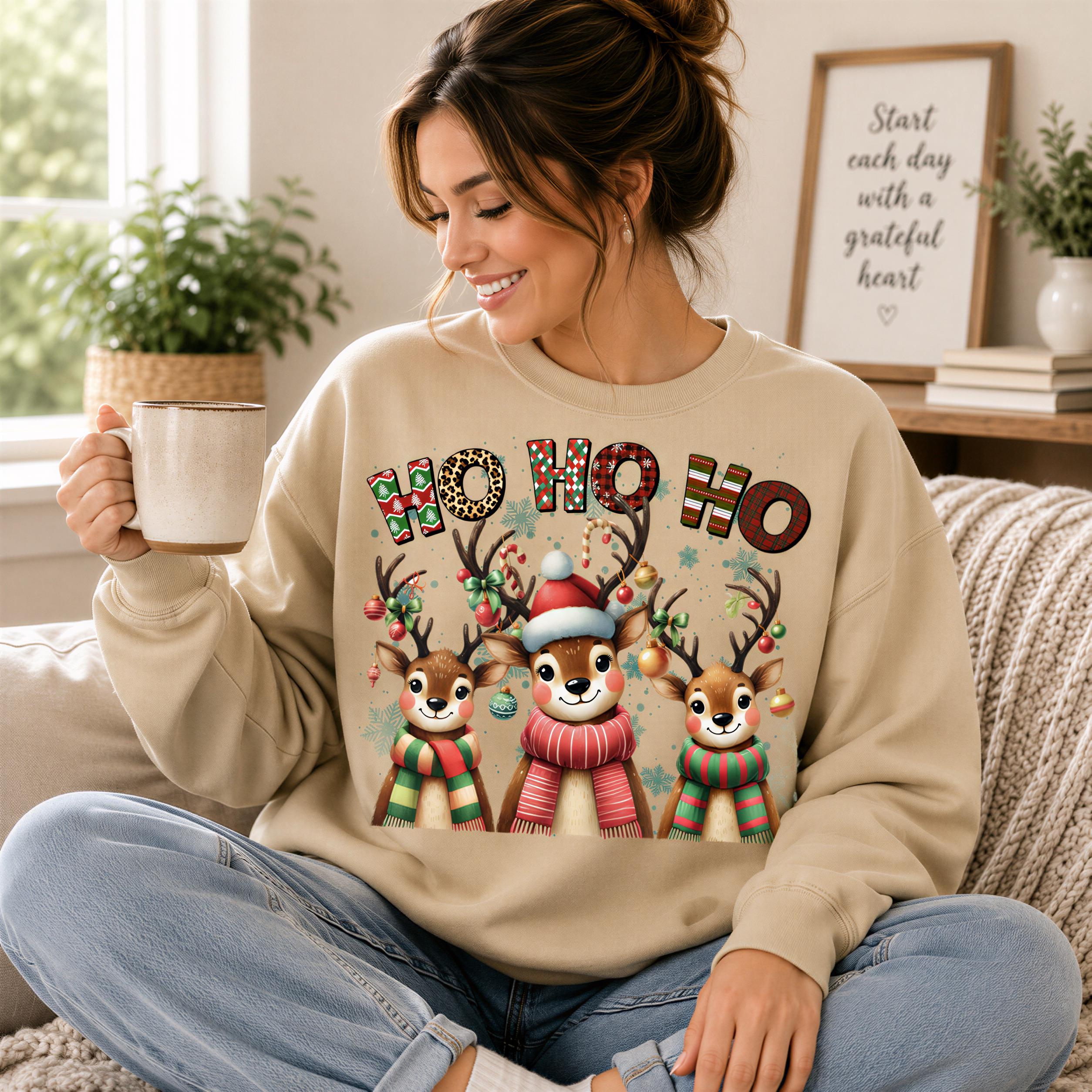 A woman sitting on a couch wearing a beige sweater with a Christmas-themed design featuring three deer wearing festive outfits and holding Christmas ornaments.