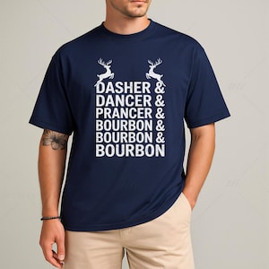 May include: Navy blue t-shirt with white text and reindeer graphics. The text reads "Dasher & Dancer & Prancer & Bourbon & Bourbon & Bourbon". A casual, short-sleeved shirt for everyday wear.