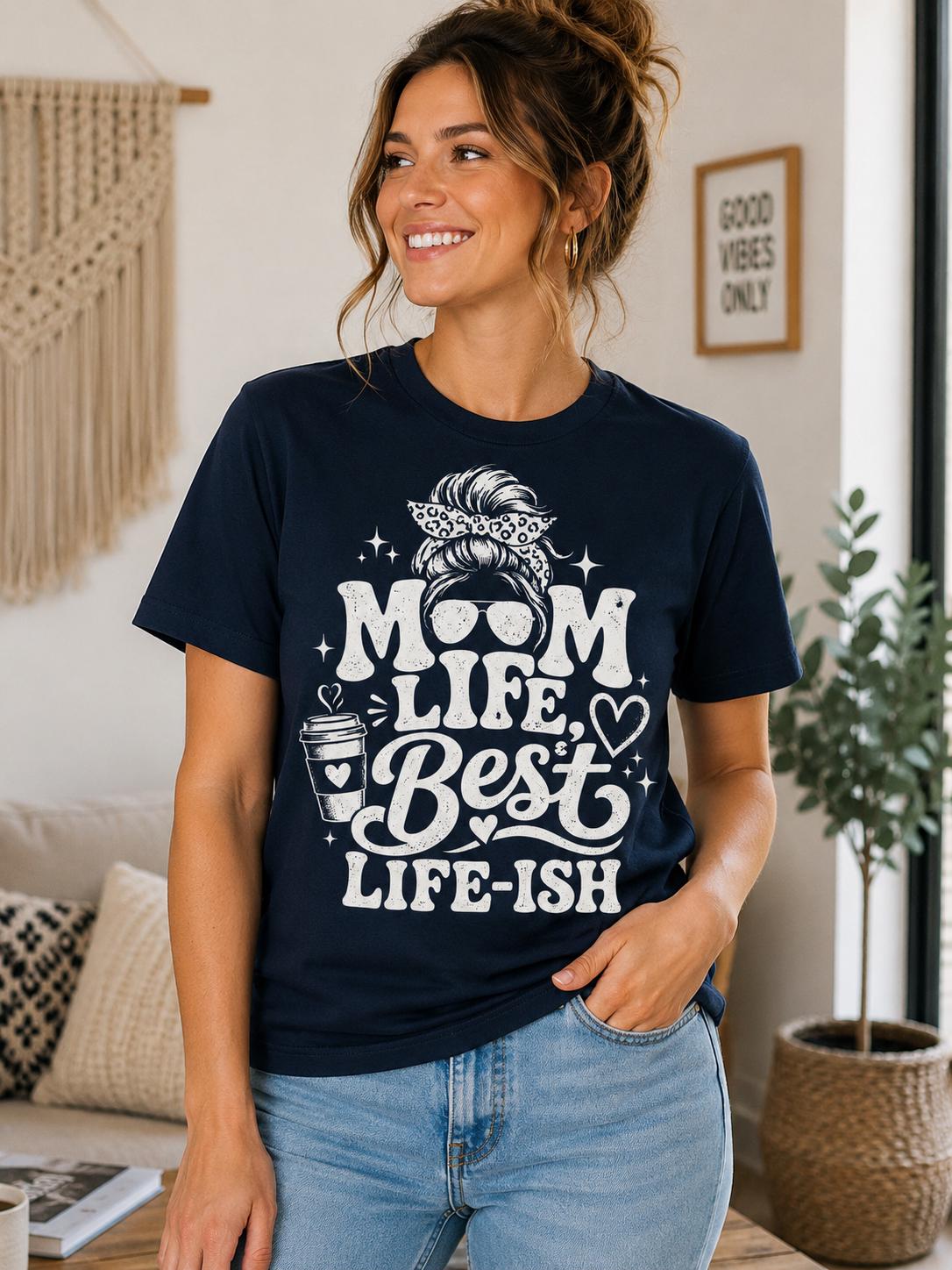 A woman wearing a navy blue t-shirt with a graphic design and text, smiling and posing in a room with a window and a plant.