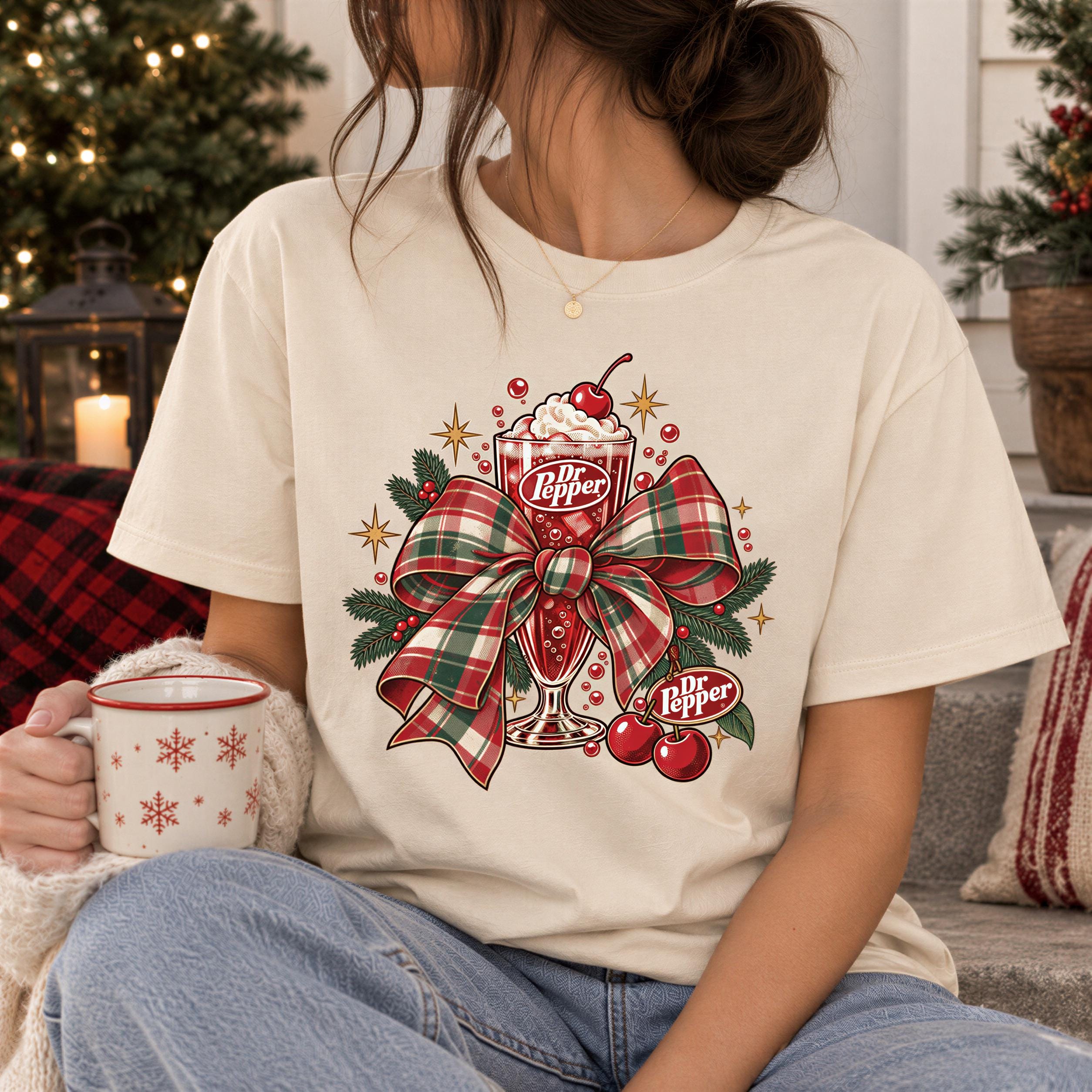 A woman wearing a white t-shirt with a graphic of a decorated ice cream cone and a ribbon, holding a mug with snowflake designs.