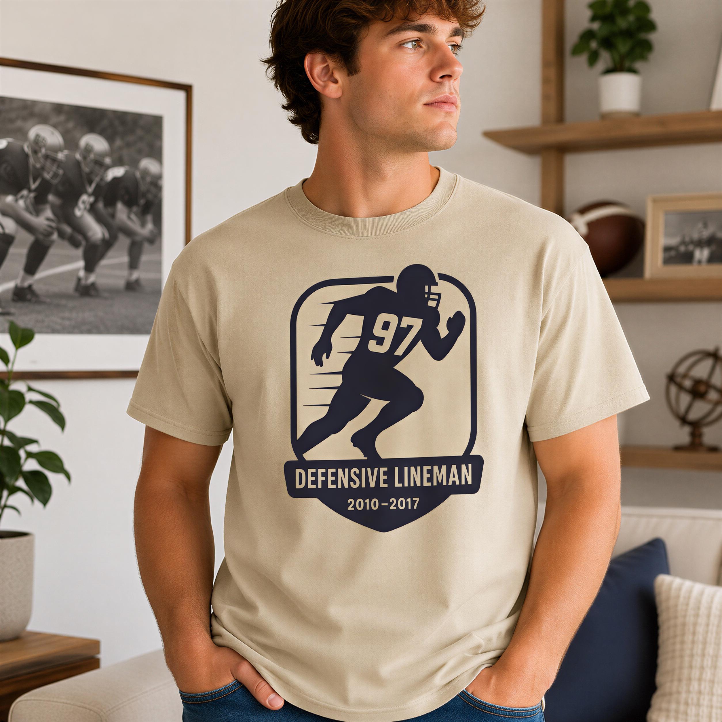 A man wearing a t-shirt with a graphic of a football player and the text "Defensive Lineman 2010-2017" is standing in a living room.