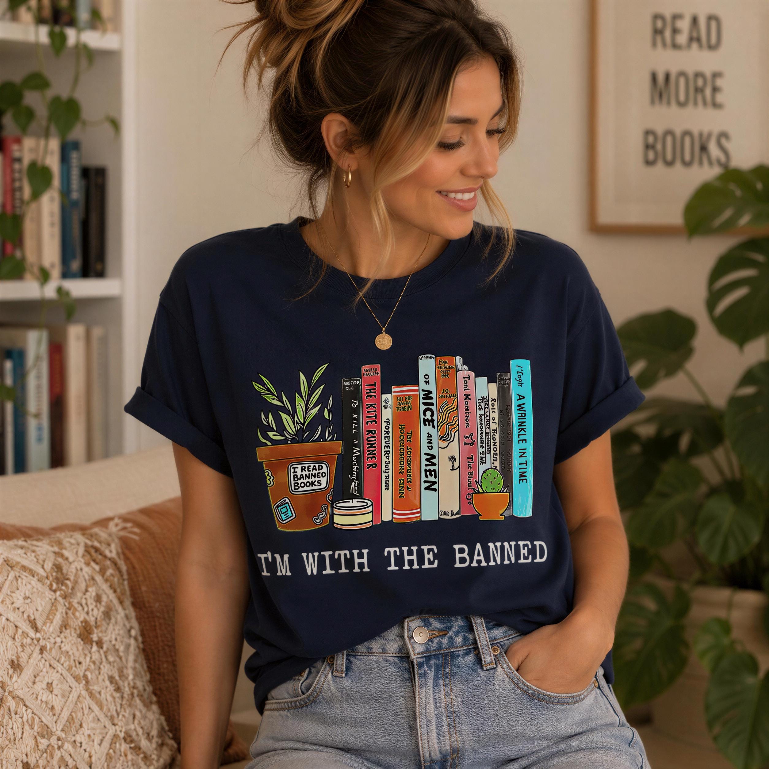 A woman wearing a navy blue t-shirt with a graphic design of a book and a plant, sitting on a couch in a room with plants and bookshelves in the background.