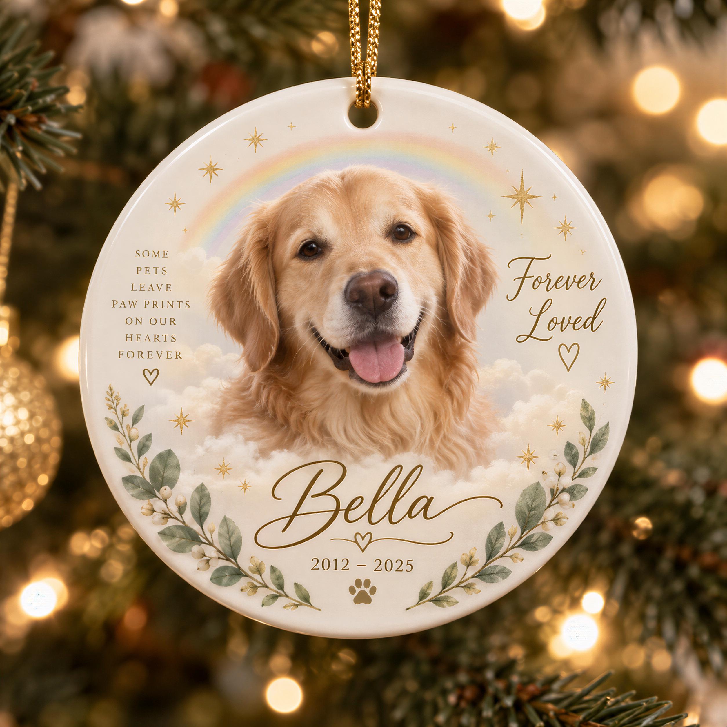 A white ornament with a golden retriever dog's face, surrounded by leaves and flowers, and a rainbow in the background. The ornament has the text "Some pets leave paw prints on our hearts forever" and "Forever loved" written on it.