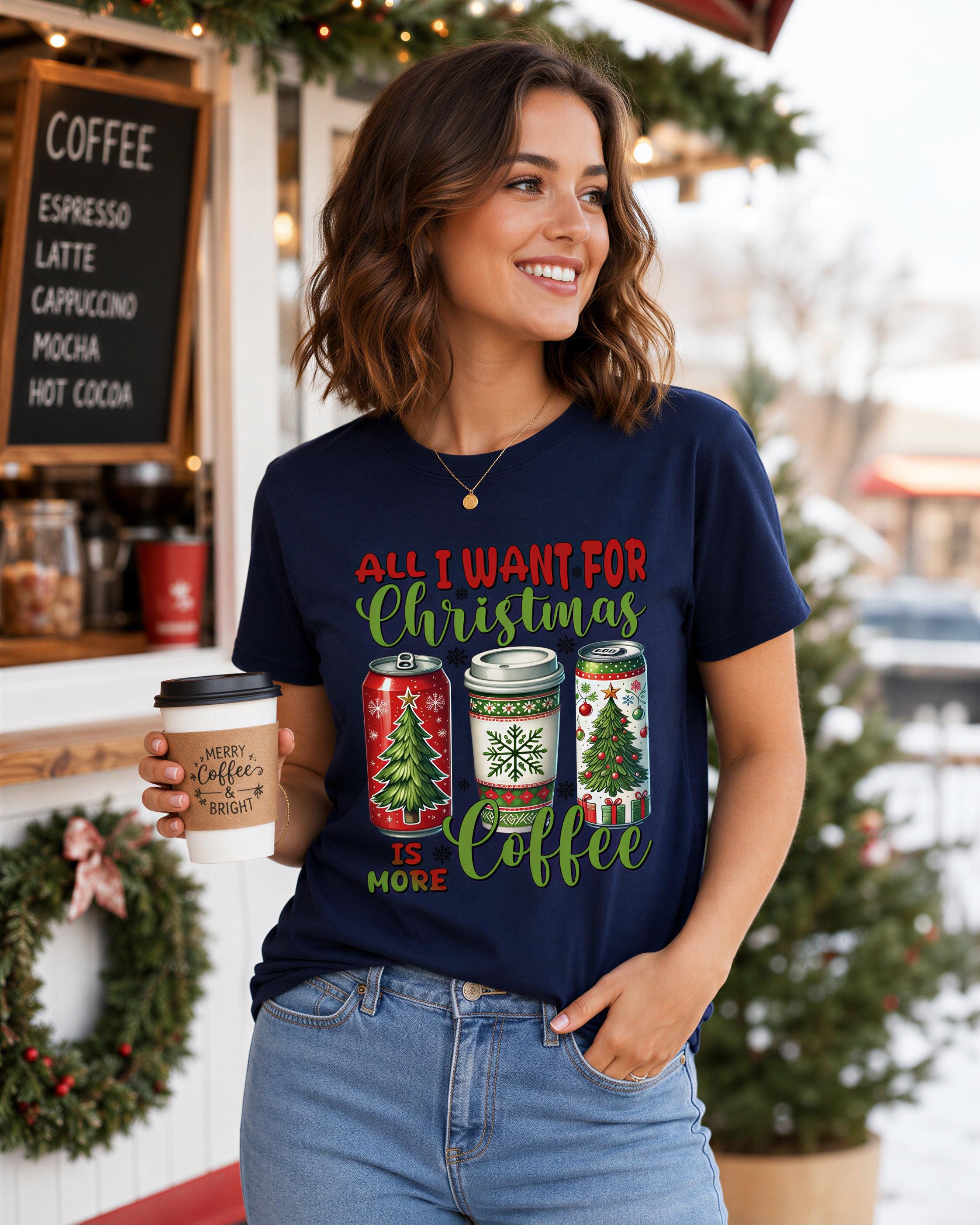 A woman wearing a navy blue t-shirt with a Christmas-themed graphic and text, holding a coffee cup and smiling.