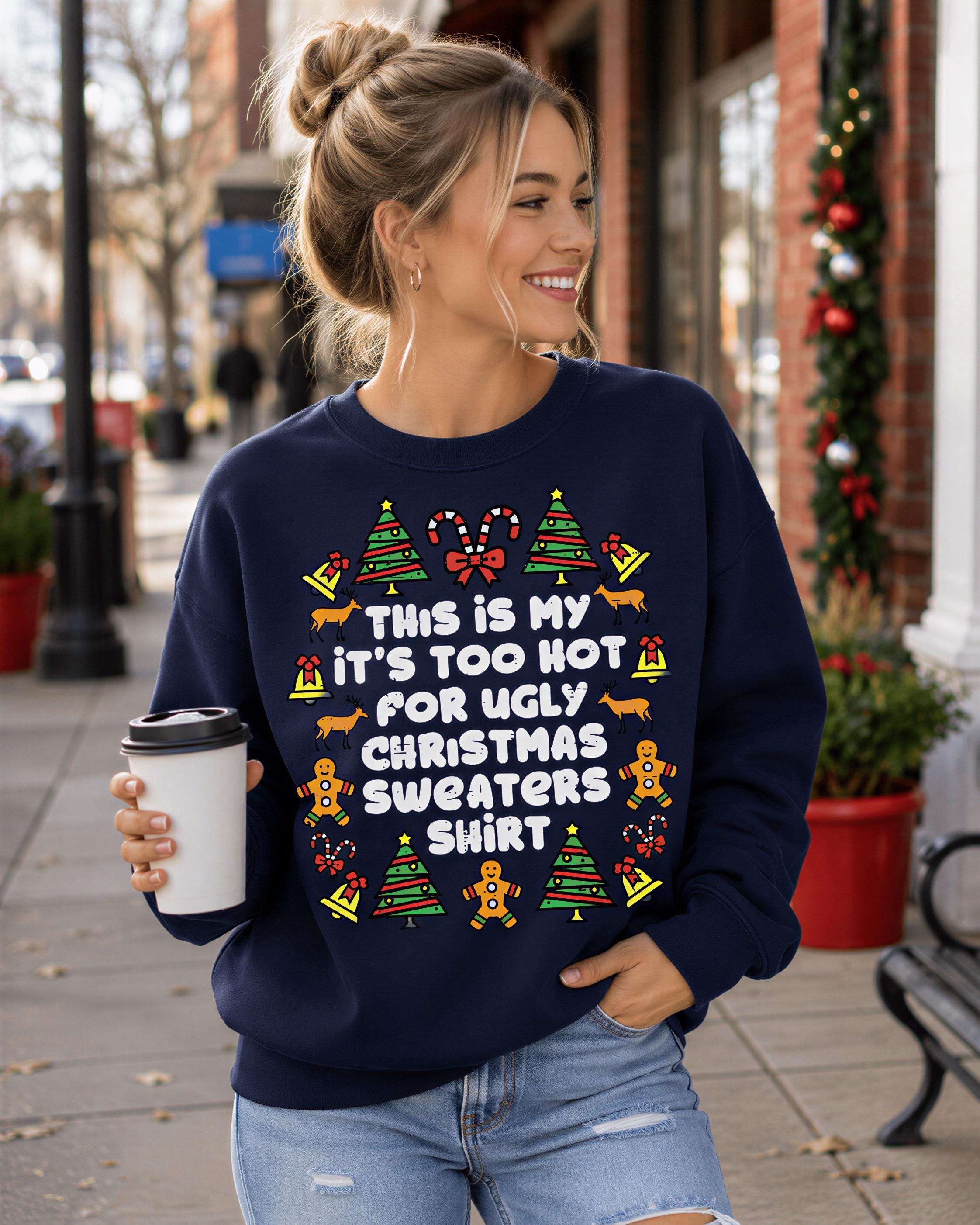 A woman wearing a navy blue sweater with a humorous Christmas-themed design and holding a coffee cup.