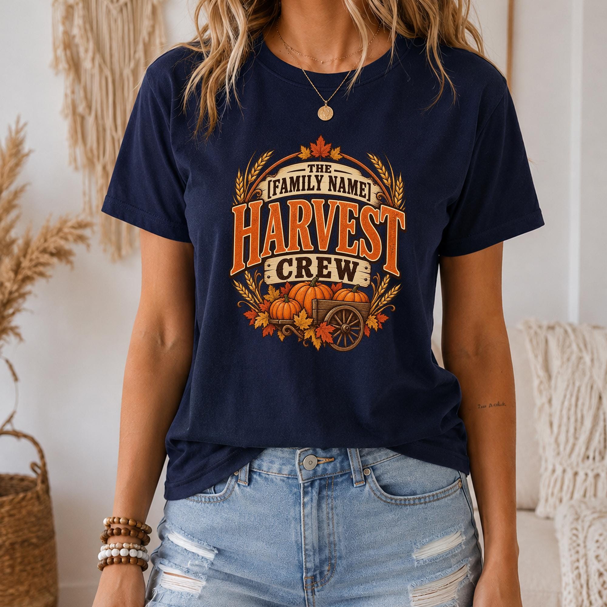 A woman wearing a navy blue t-shirt with a graphic design that says "The Harvest Crew" and features a wagon filled with pumpkins and autumn leaves.