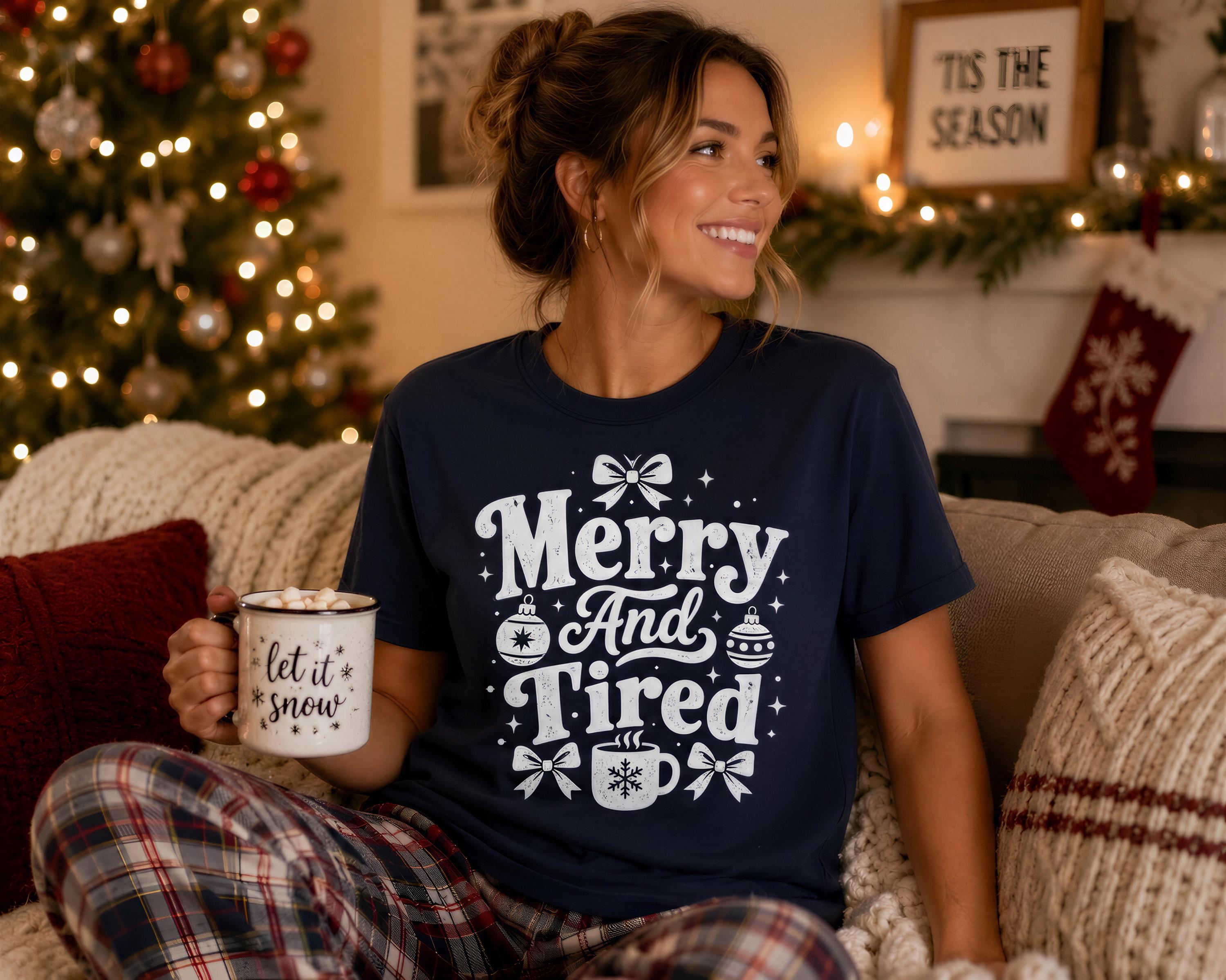 A woman wearing a navy blue t-shirt with a white design and text, sitting on a couch and holding a mug with a snowflake design.