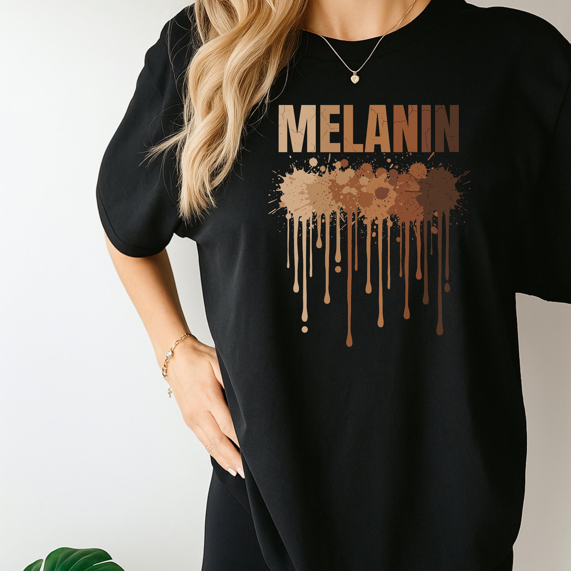 A person wearing a black t-shirt with the word "MELANIN" printed on it, along with a graphic design featuring dripping brown paint or liquid.